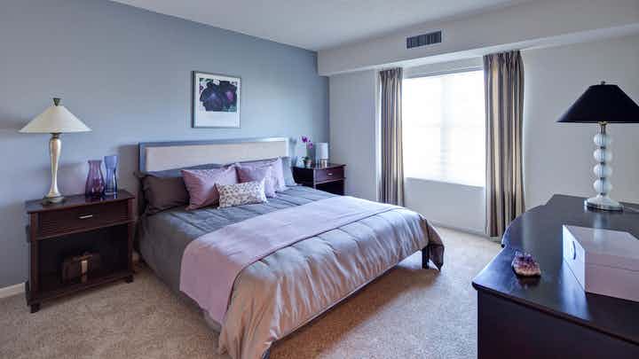AMLI at Seven Bridges bedroom with grey decor and pink accents featuring a large bright window with flowing curtains