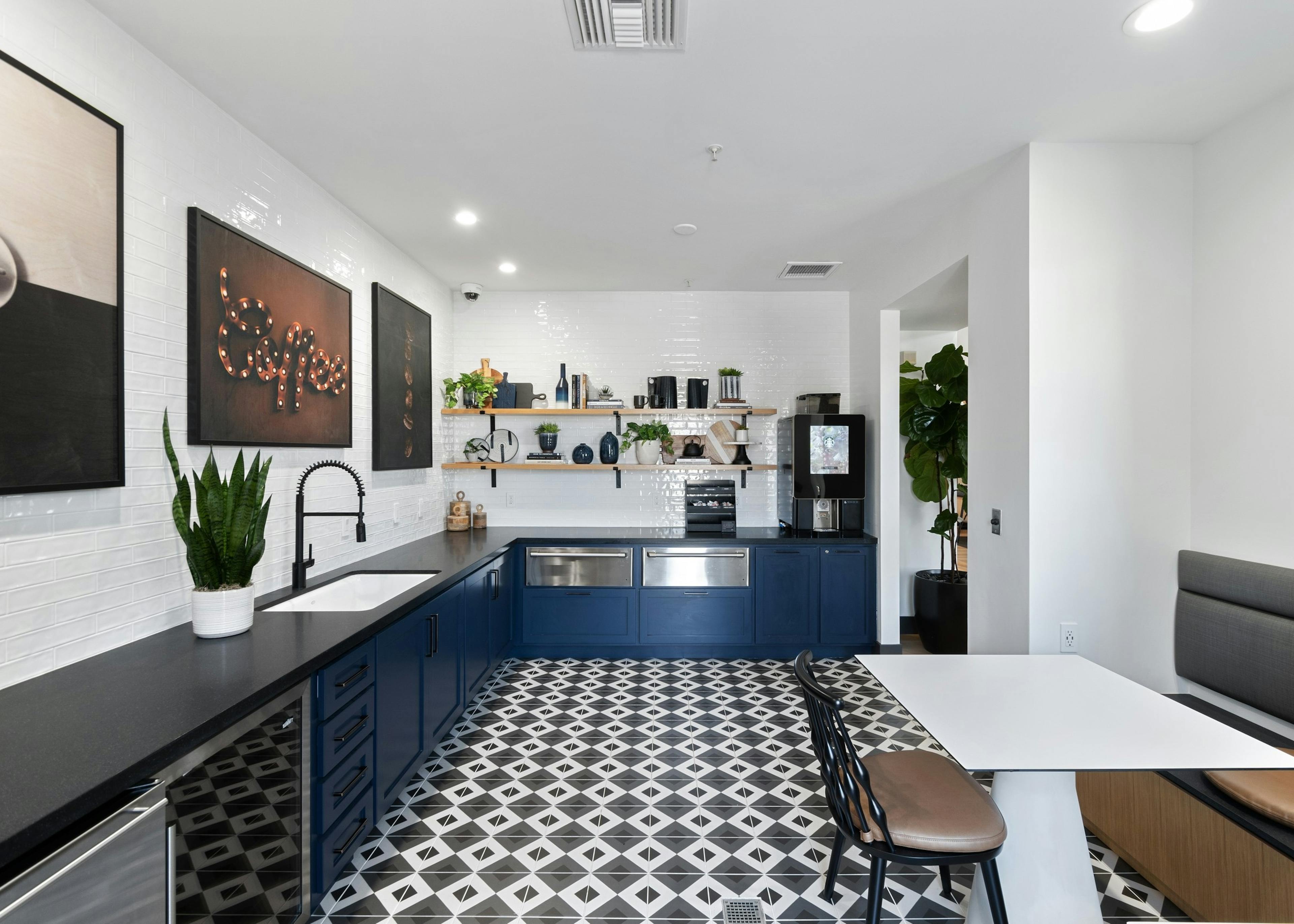 Java bar at AMLI Spanish Hills apartments with blue cabinets and black countertop and pictures shelving on white tile wall