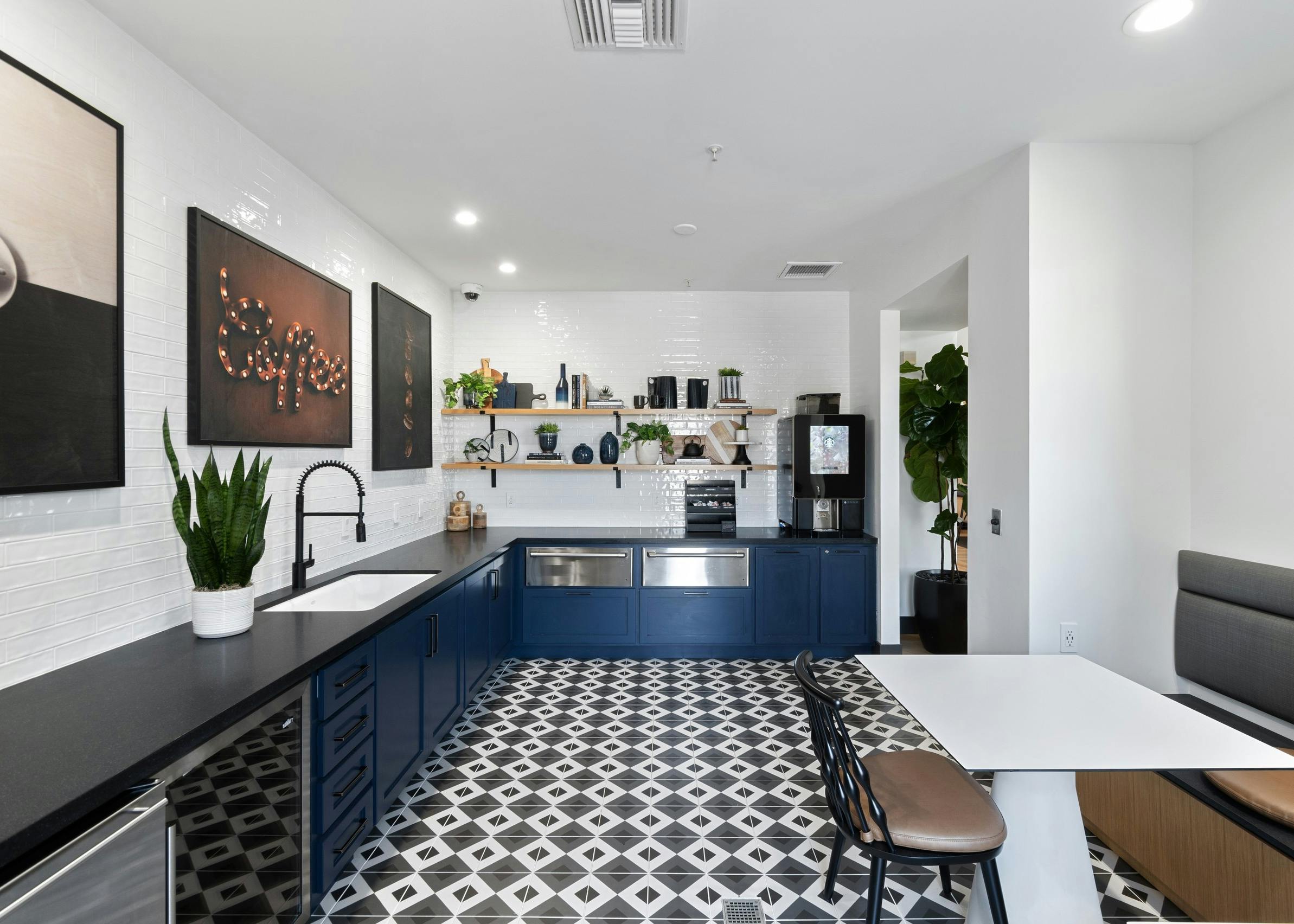 Java bar at AMLI Spanish Hills apartments with blue cabinets and black countertop and pictures shelving on white tile wall
