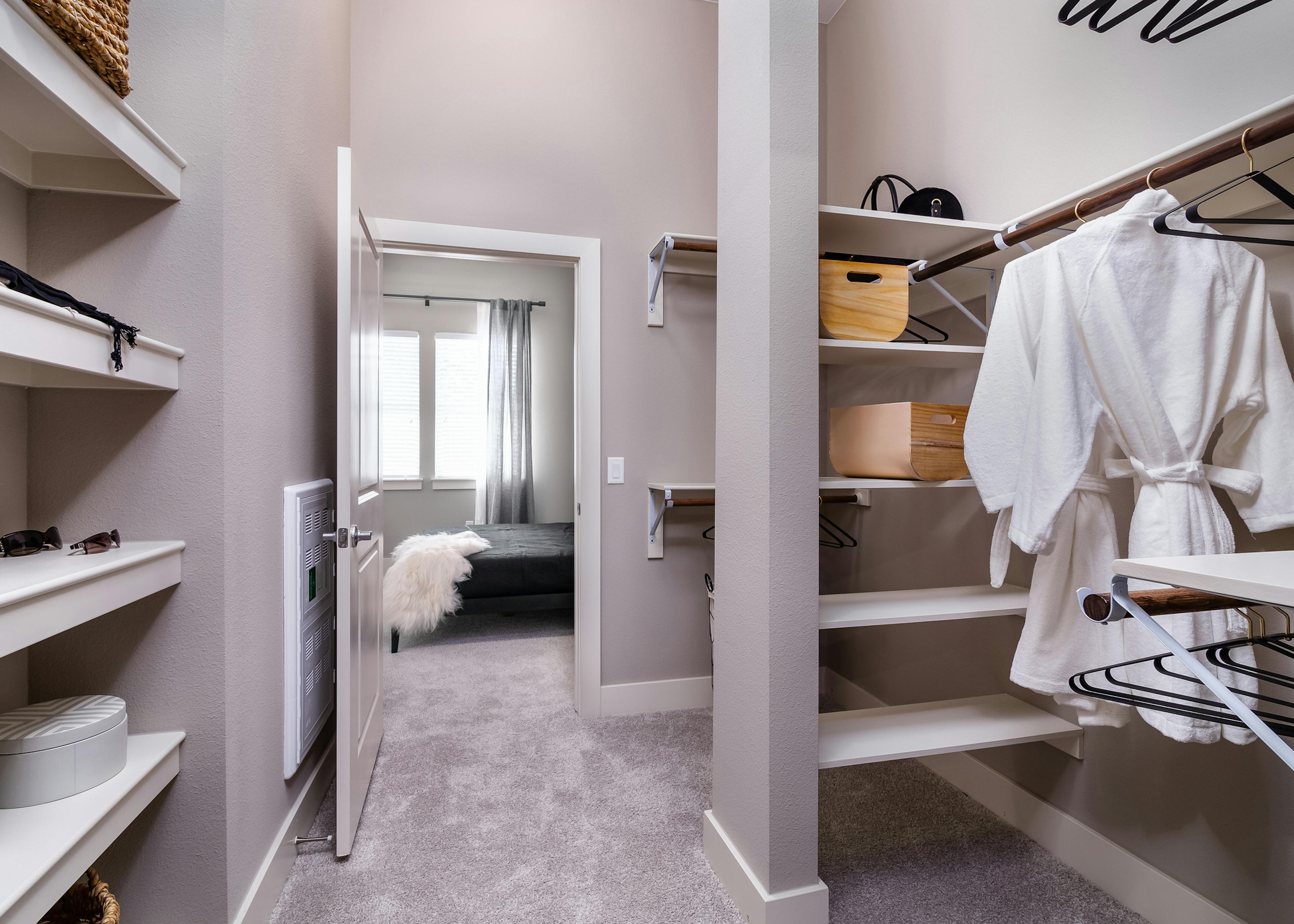 Interior of AMLI Littleton Village apartment’s walk-in closet with shelving, wicker laundry hamper and peek into bathroom