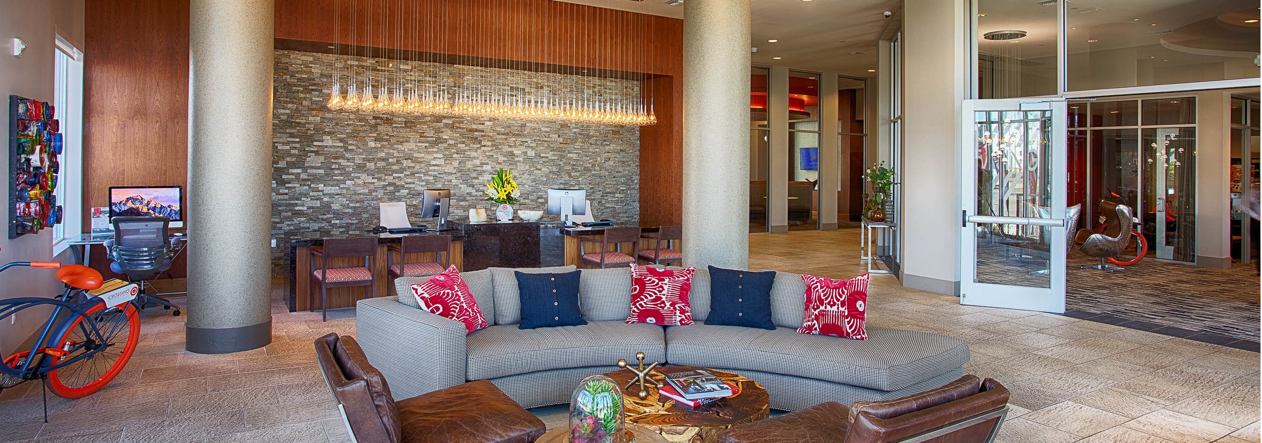 Interior view of the lobby at AMLI Denargo Market apartments with couches and chairs and a staff desk with hanging lights