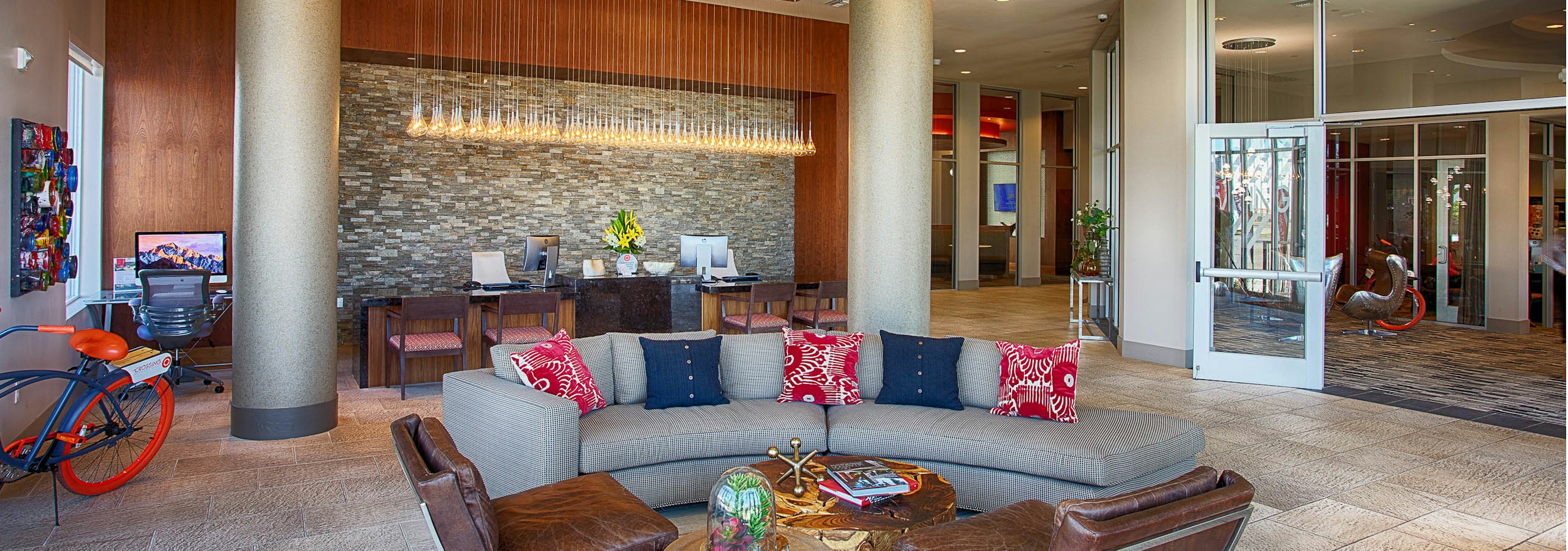 Interior view of the lobby at AMLI Denargo Market apartments with couches and chairs and a staff desk with hanging lights