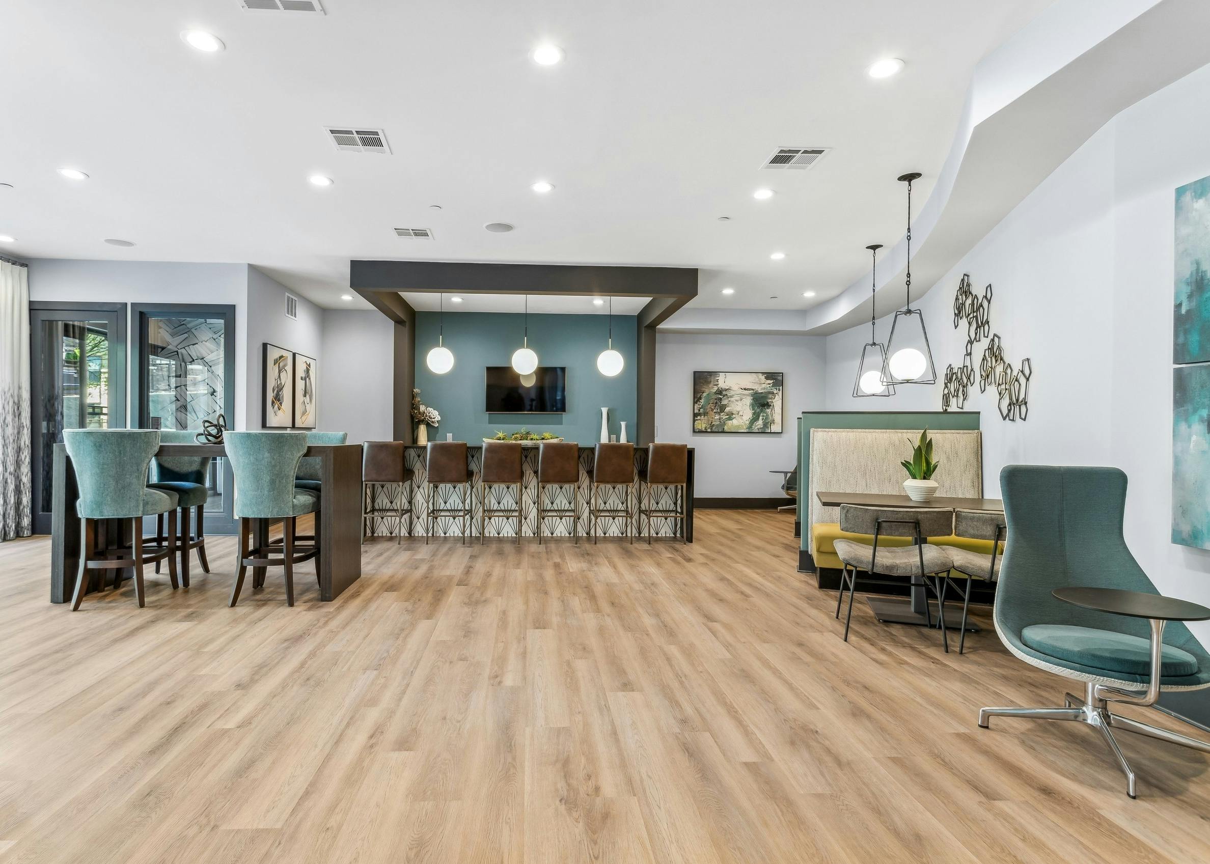 AMLI Parkside co-working space with island with stools facing a blue wall with a TV and various seating set on wood floors