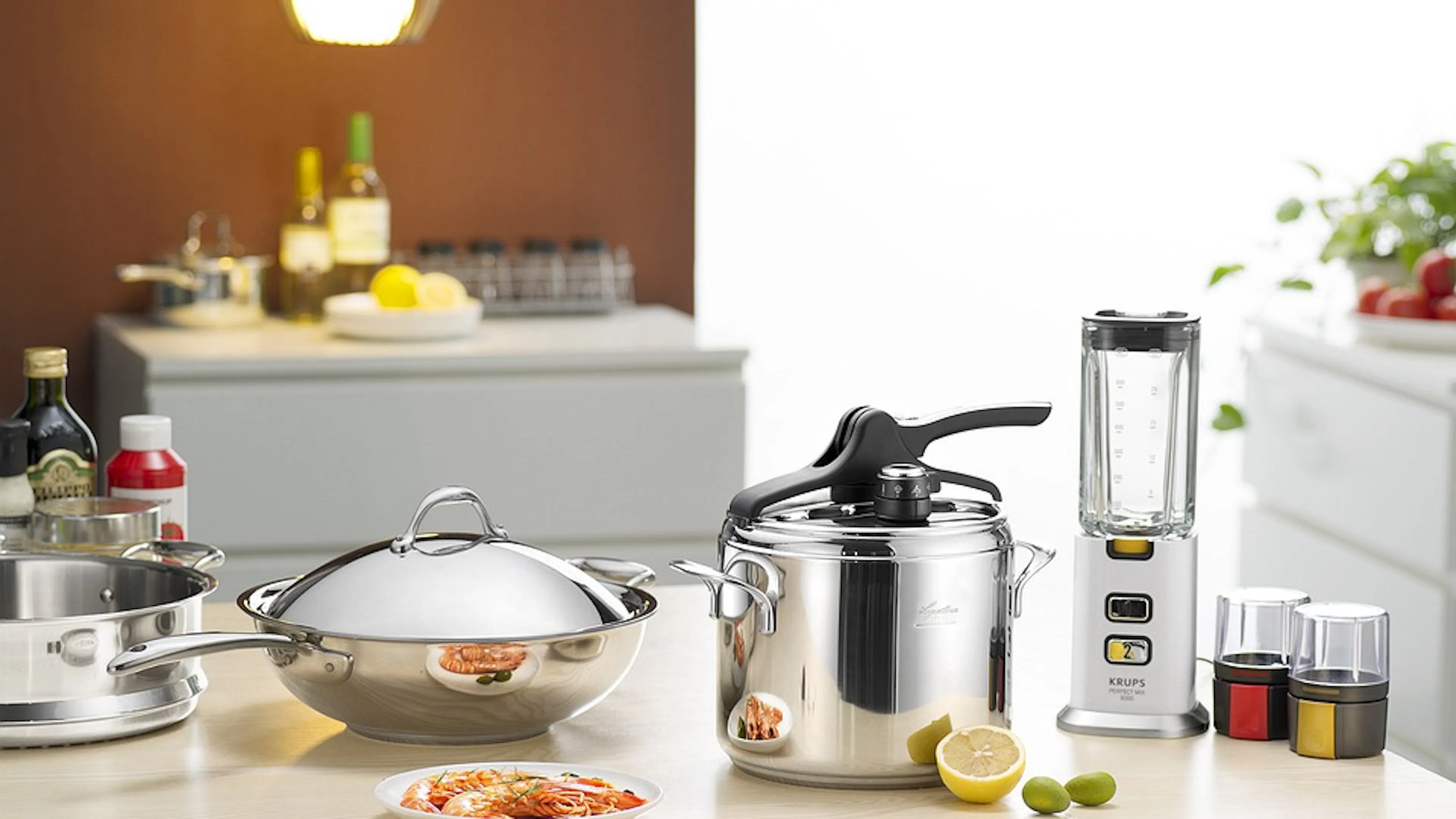 A few stainless steel pots and pans on a white quartz countertop next to a plate of spaghetti