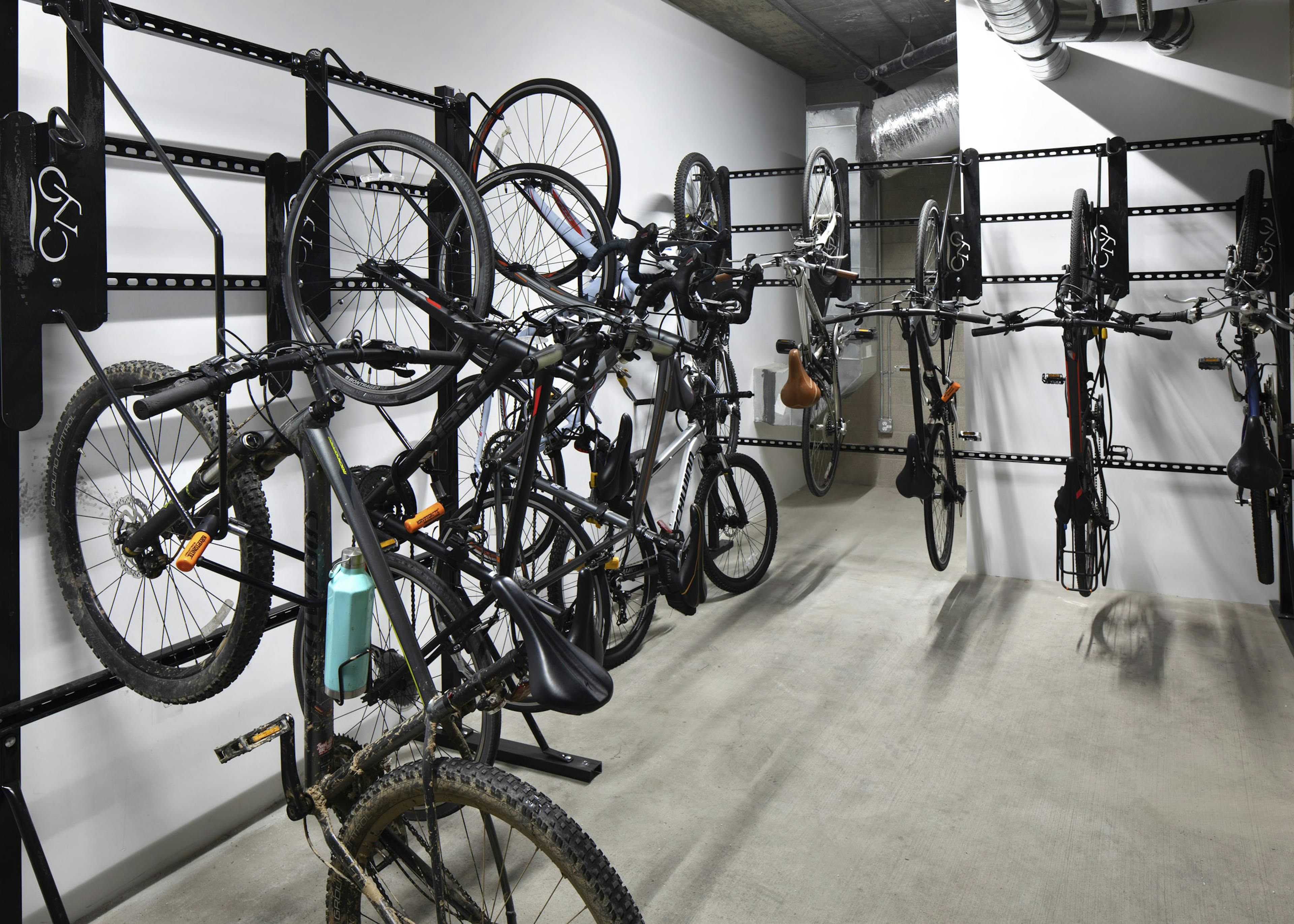 Interior view of the private bicycle storage room at AMLI Park Broadway apartment building with multiple hanging racks 