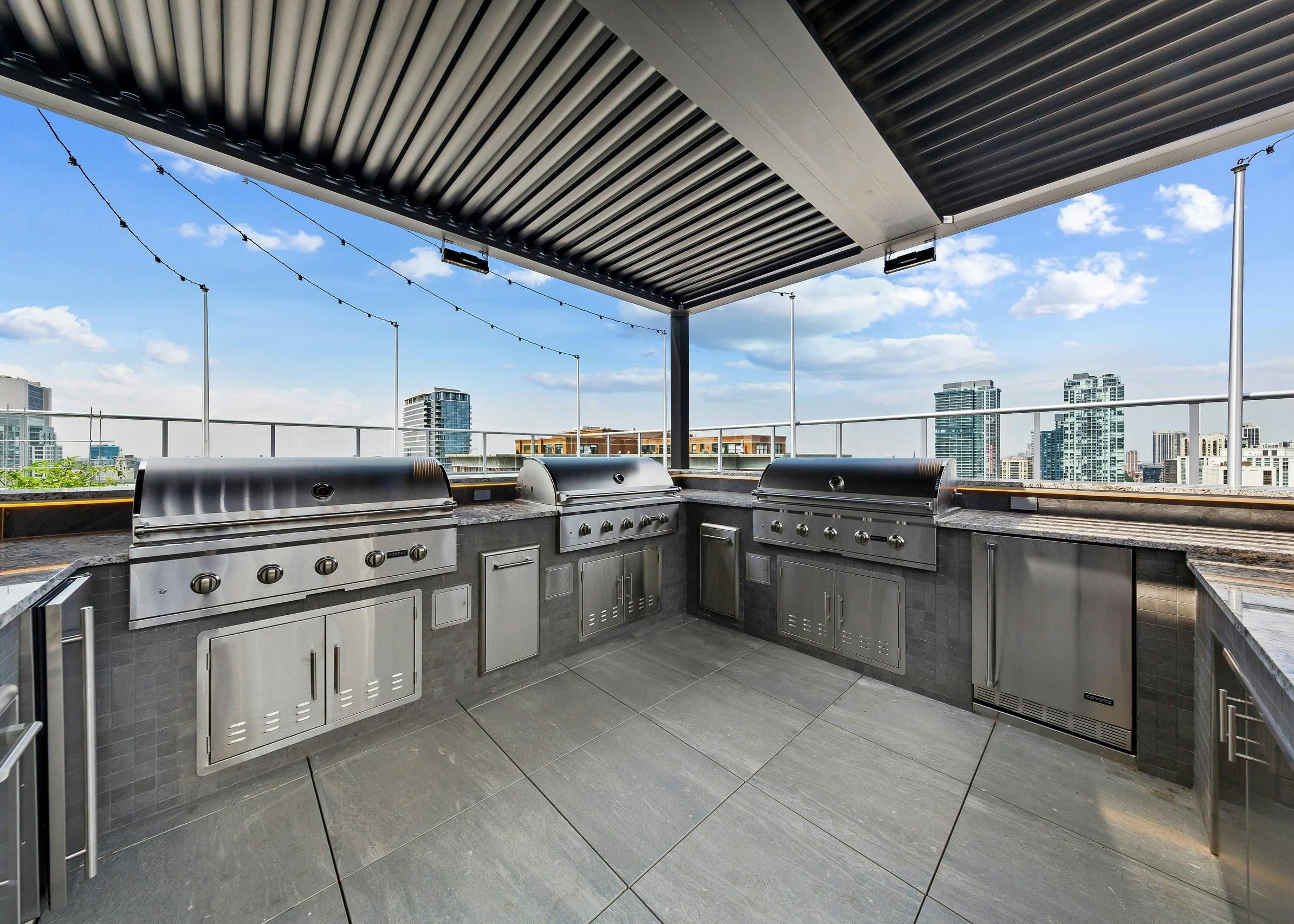 Spacious rooftop stainless steel grill station at the AMLI 808 apartment building surrounded by gorgeous Chicago skyline