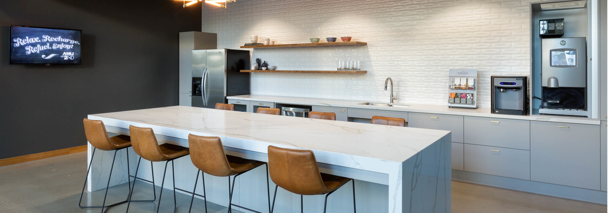 AMLI on 2nd java cafe with grey cabinets and white counters with coffee maker and island with four brown leather barstools