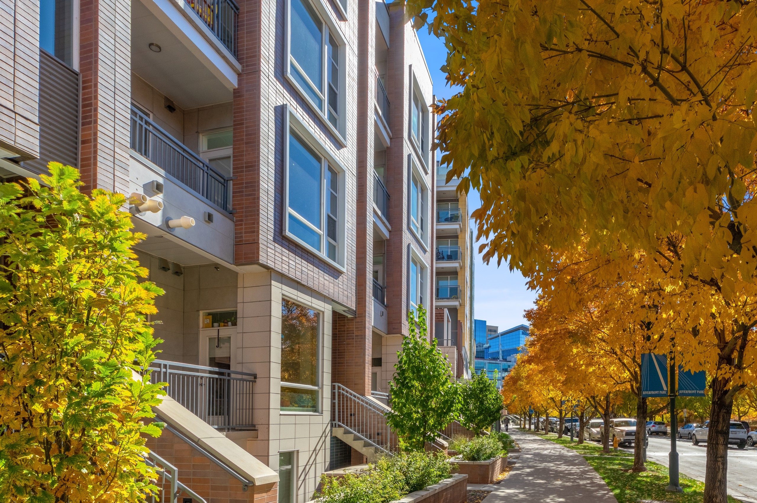 Close up view of AMLI Riverfront Green townhome exterior with spacious balconies and windows lined by colorful autumn trees