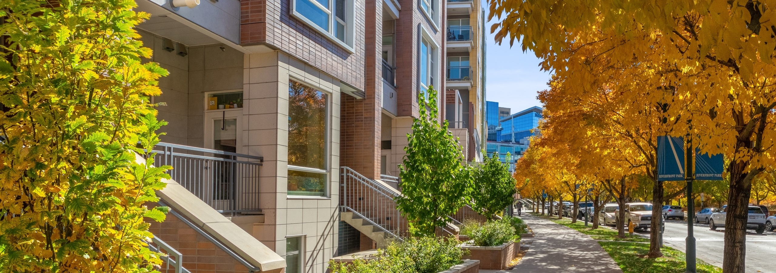 Close up view of AMLI Riverfront Green townhome exterior with spacious balconies and windows lined by colorful autumn trees