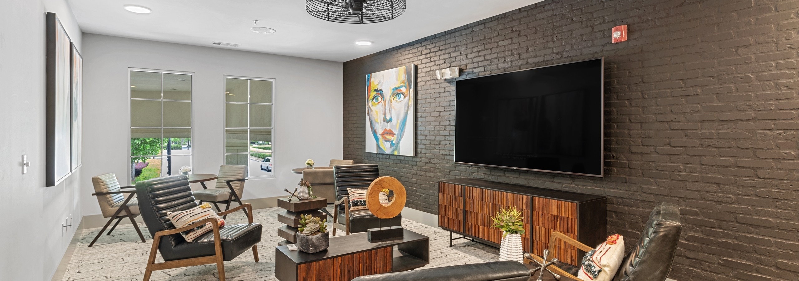 Resident lounge at AMLI North Point apartments with painted brick wall and TV on wall with armchair seating and side window