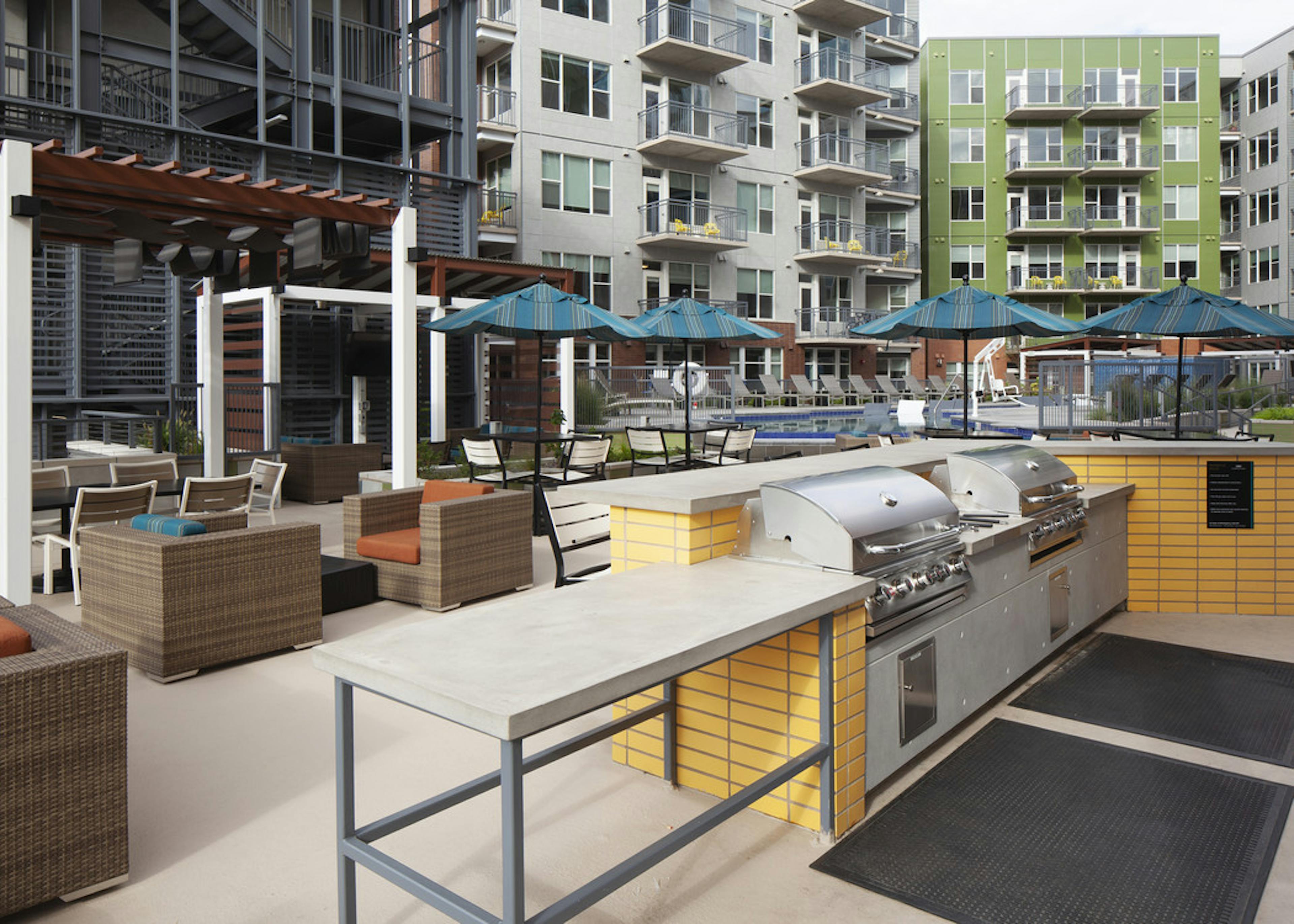 Poolside barbeque grills at AMLI Riverfront Green apartments with a cabana area with various comfortable chairs and tables