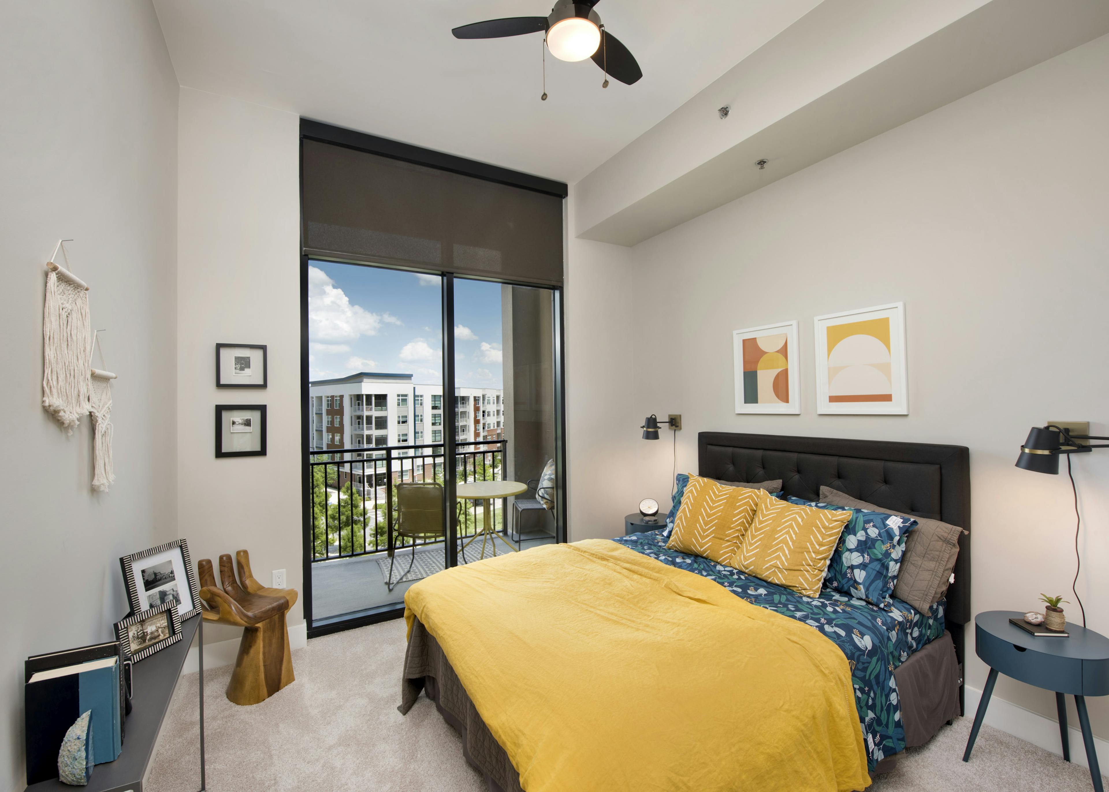 AMLI Lenox bedroom with floor to ceiling window and bed with yellow comforter and blue flowered sheets and blue nightstands 