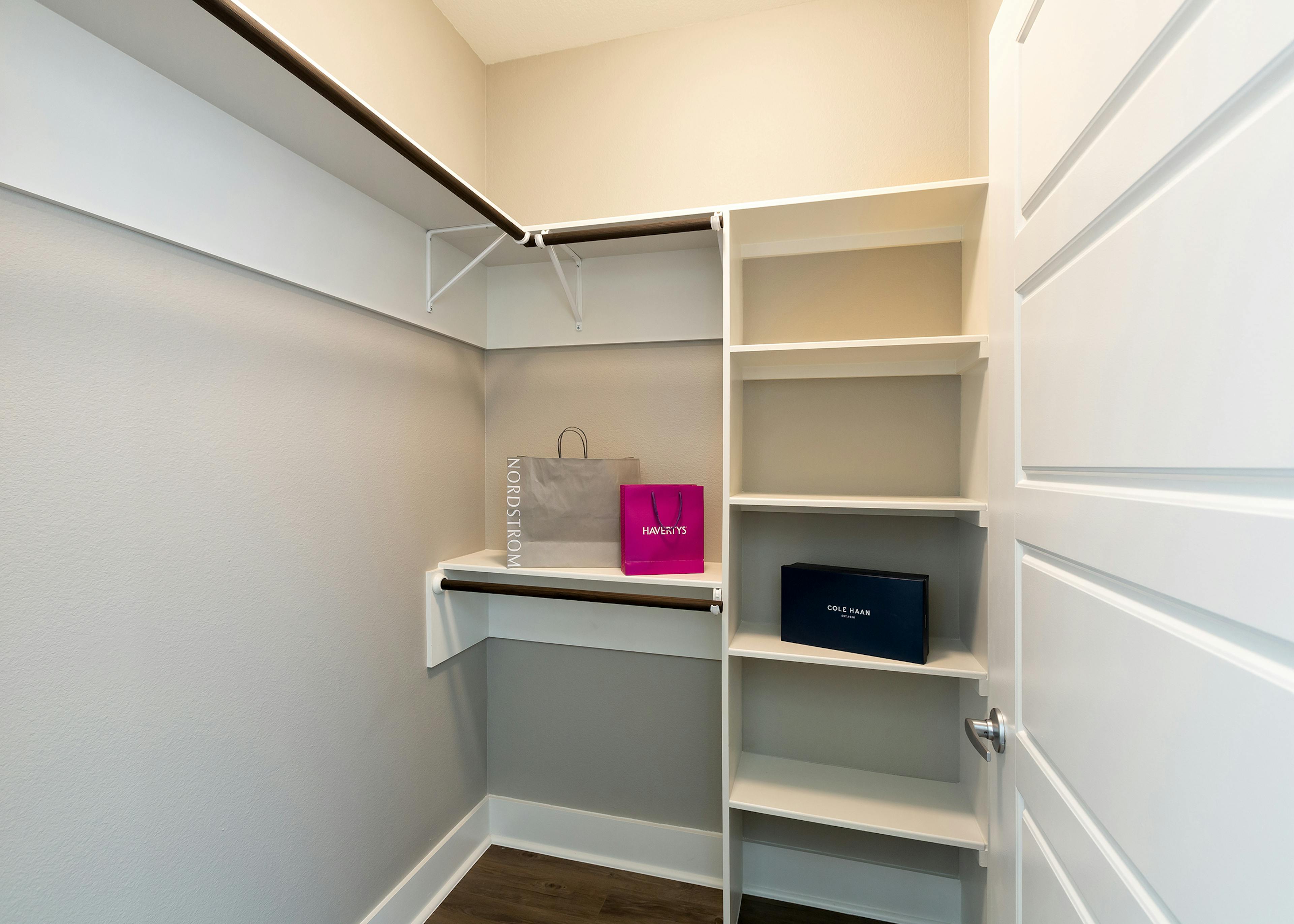 Interior view of walk in apartment closet at AMLI South Shore with built in shelving and ample space to hang clothing