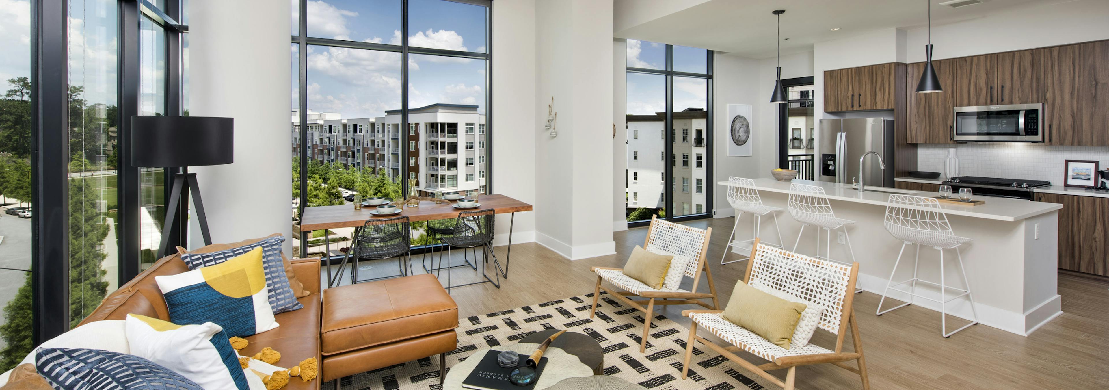 AMLI Lenox apartment interior with large windows and brown sofa with colorful pillows and dining area and island kitchen