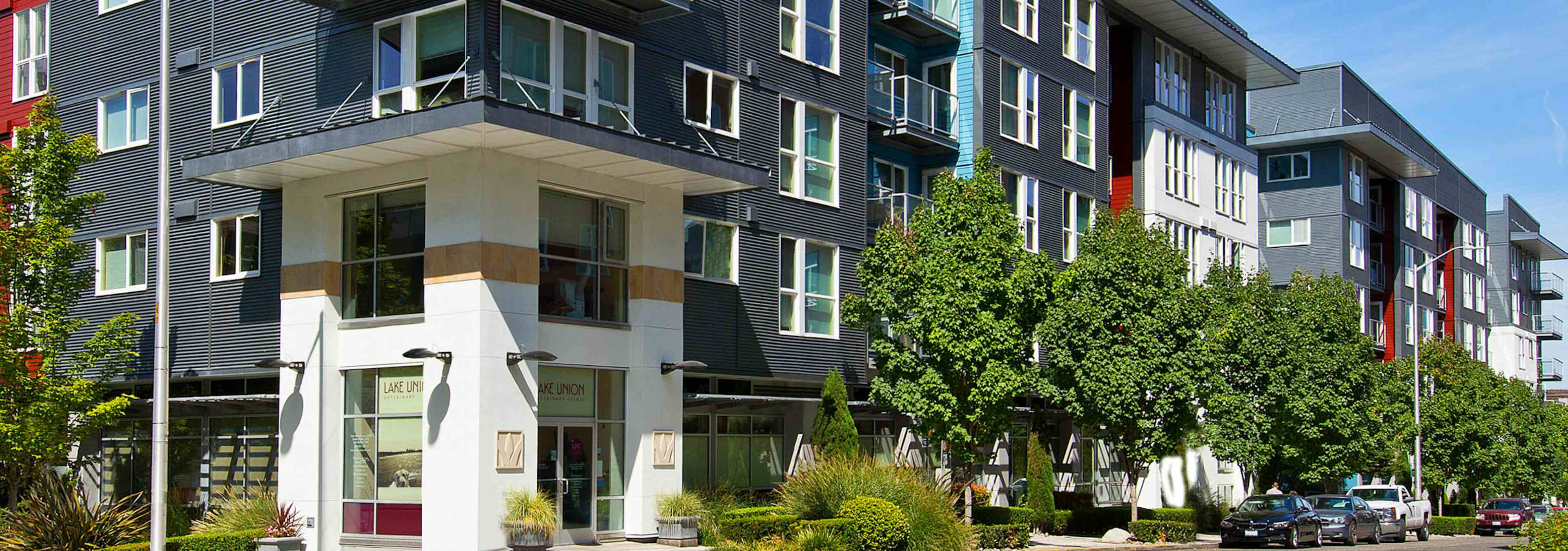 Exterior of AMLI 535 apartment building with retail and lush trees and bushes with side walk