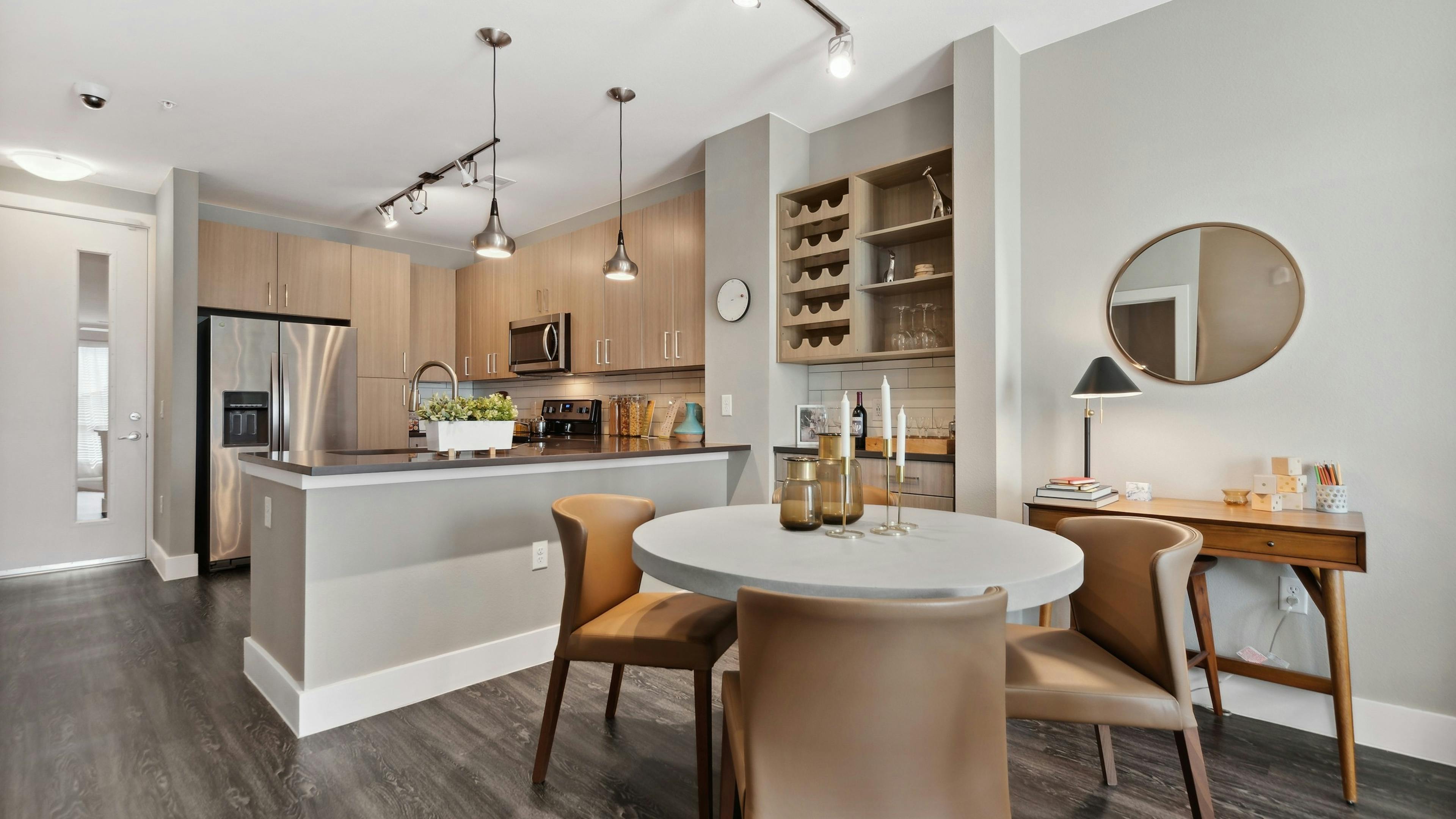 Dining room with bar area and wine rack at AMLI Dry Creek with a kitchen with stainless steel appliances and overhead lighting