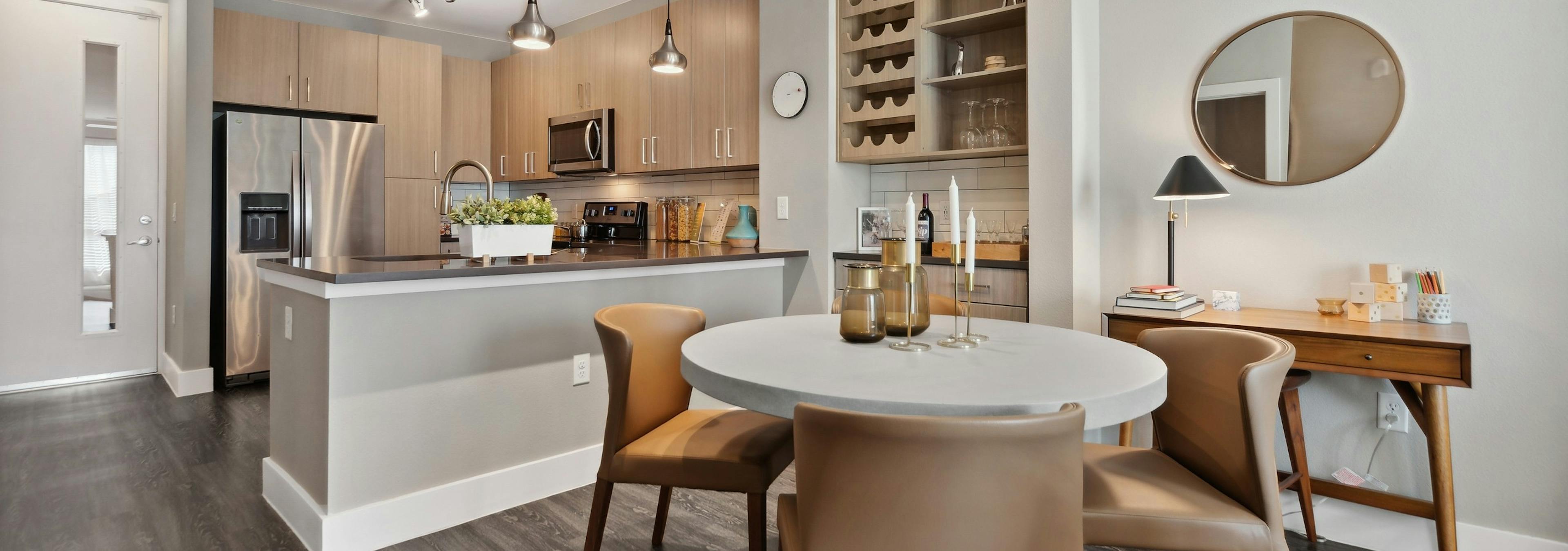 Dining room with bar area and wine rack at AMLI Dry Creek with a kitchen with stainless steel appliances and overhead lighting