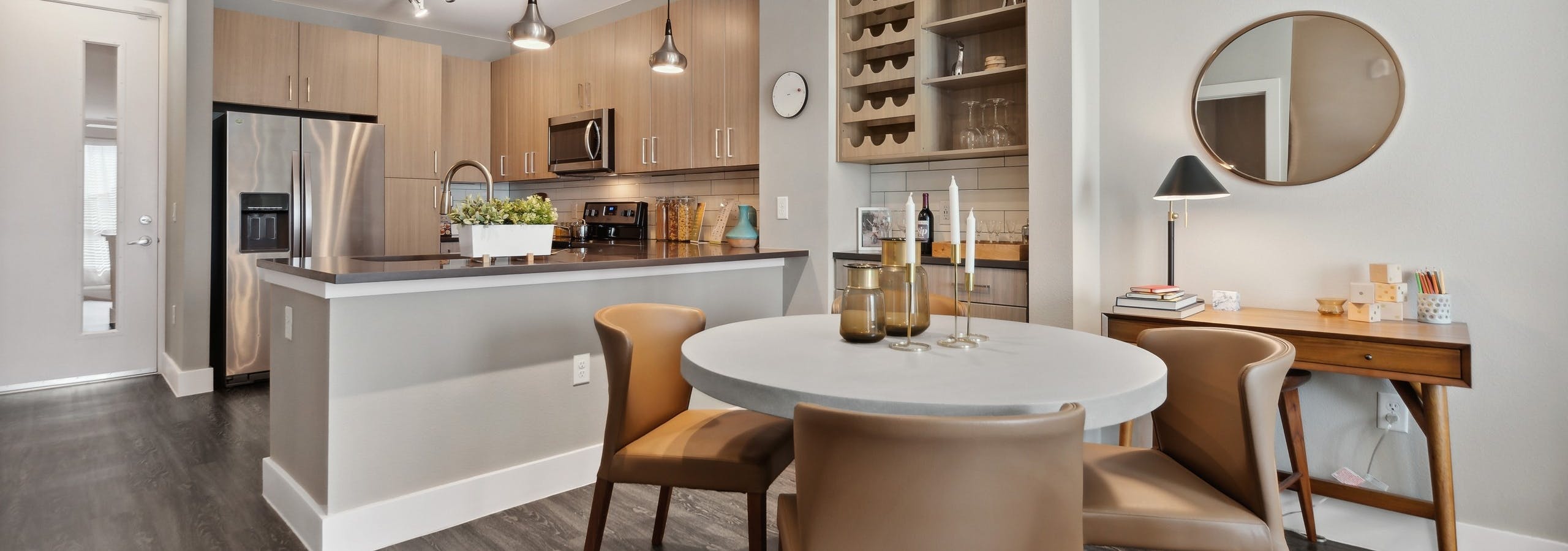 Dining room with bar area and wine rack at AMLI Dry Creek with a kitchen with stainless steel appliances and overhead lighting