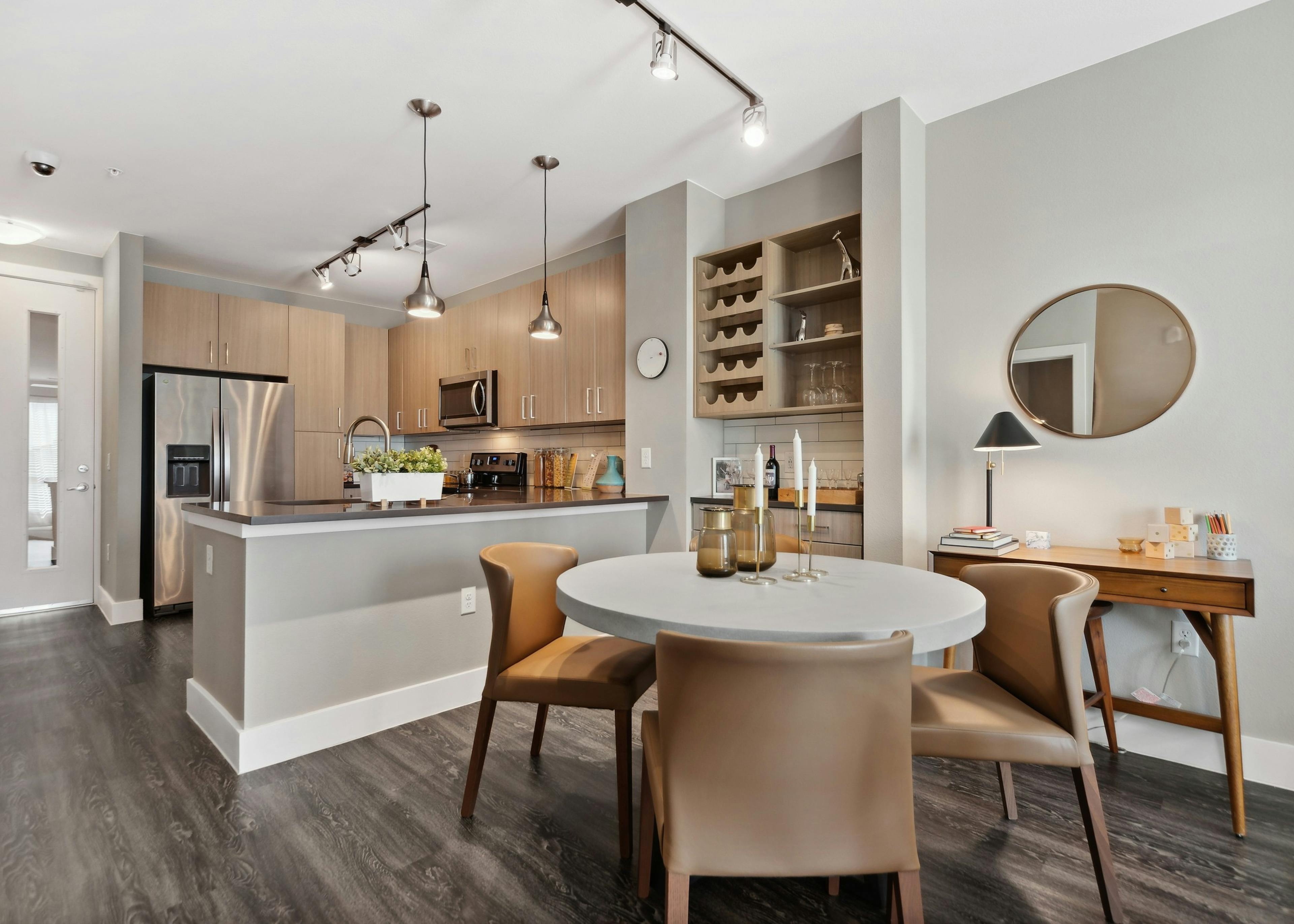 Dining room with bar area and wine rack at AMLI Dry Creek with a kitchen with stainless steel appliances and overhead lighting