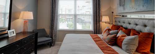 AMLI Deerfield bedroom with window and decorated with king size bed and dresser with a chair in a corner and lamps