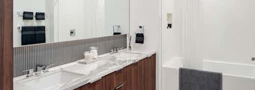 Interior view of AMLI Fountain Place apartment bathroom with double vanity and Italian made custom cabinetry with shower tub