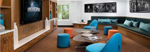 Interior view of media lounge at AMLI Uptown Orange apartments with various blue and orange seating options and big screen TV