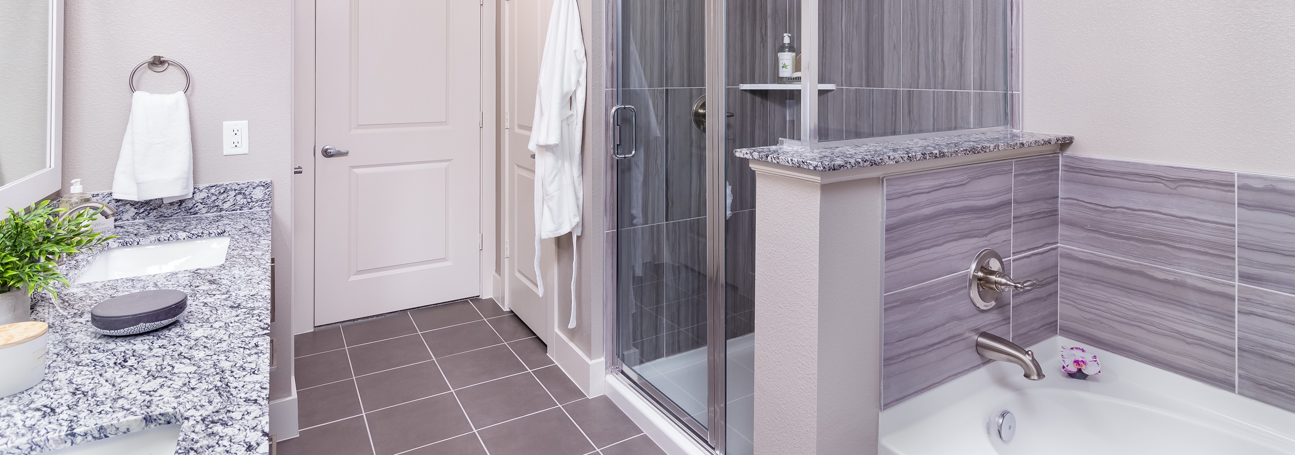 Interior of AMLI Littleton Village apartment bathroom with granite countertops double vanity, soaking tub and walk-in shower