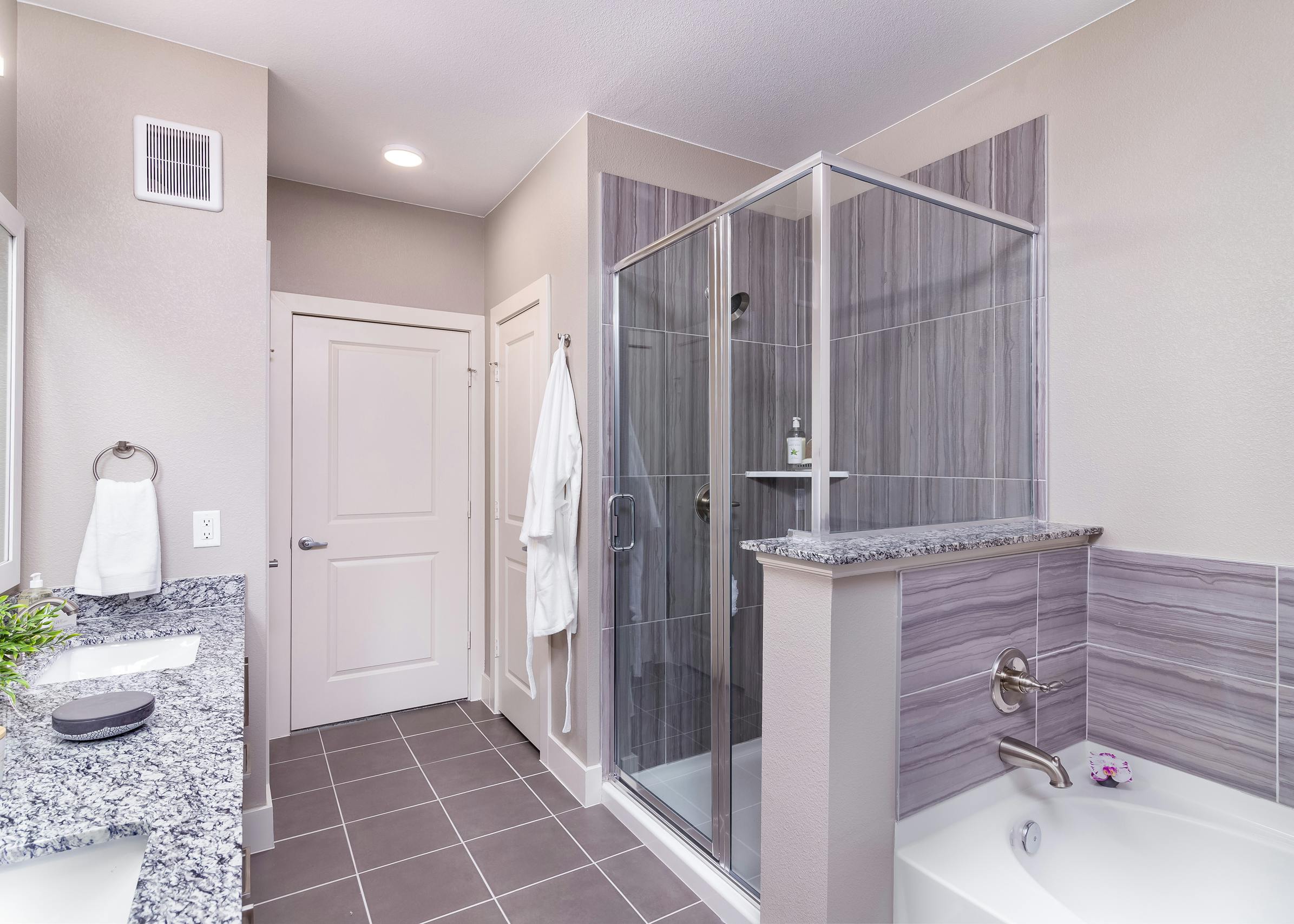 Interior of AMLI Littleton Village apartment bathroom with granite countertops double vanity, soaking tub and walk-in shower