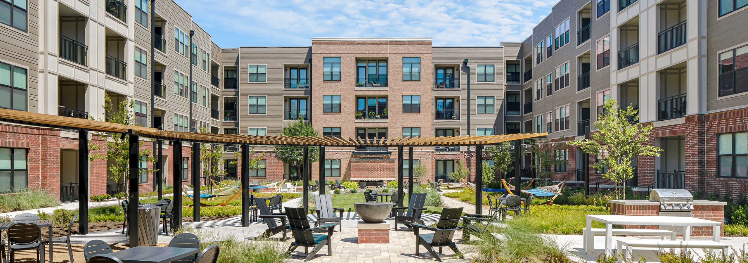AMLI Addison courtyard with firepit at center surrounded by Adirondack chairs with grill and hammocks and other seating