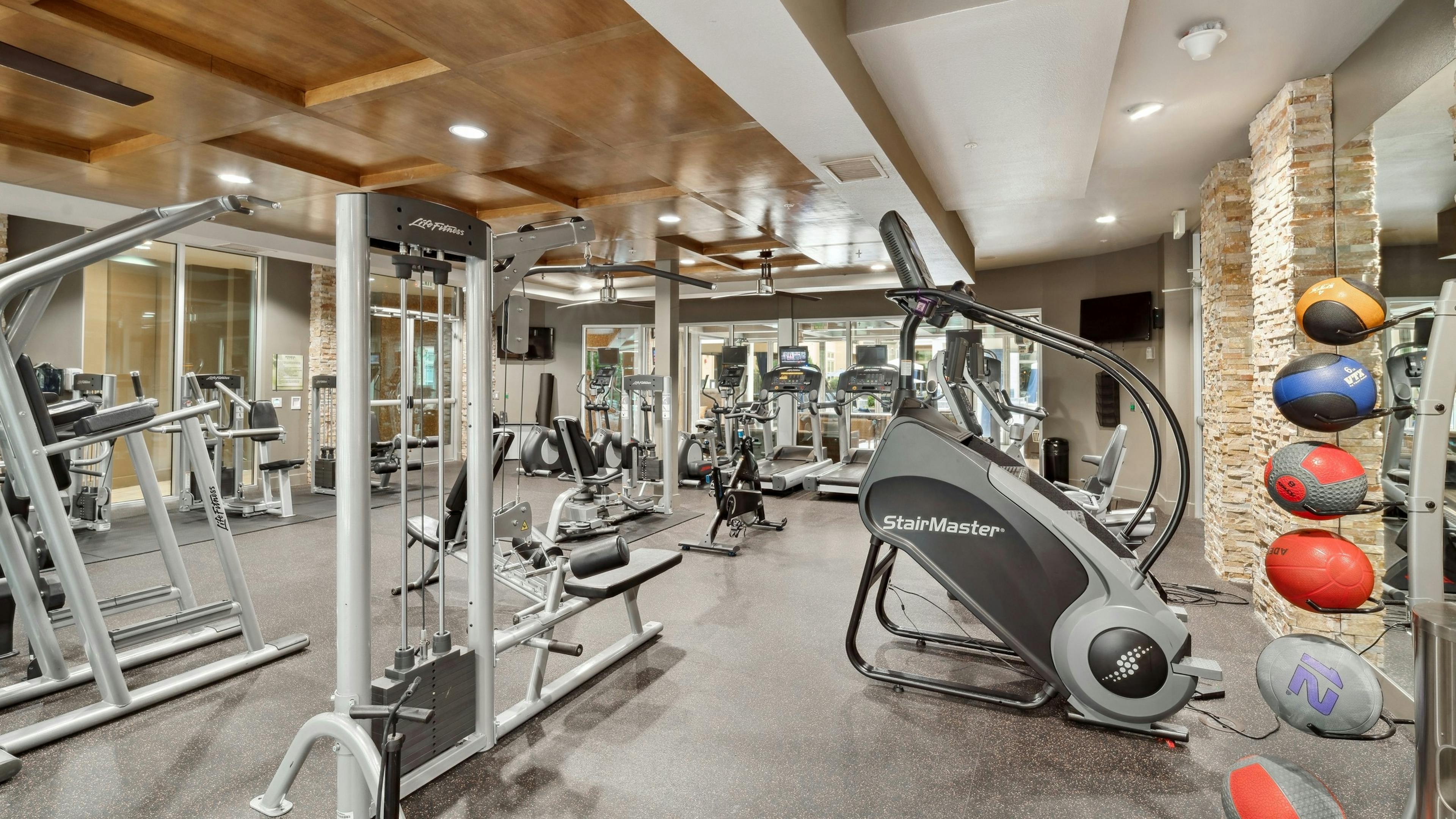 Interior view of a fitness center at AMLI RidgeGate with strength training equipment and cardio equipment and medicine balls