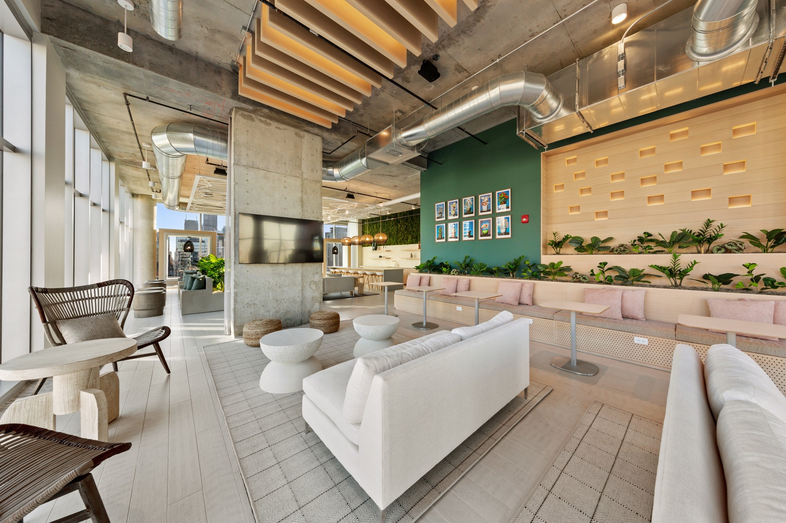 AMLI 808 resident lounge with neutral furnishings and a loft ceiling with vibrant green plants lining the wall in background