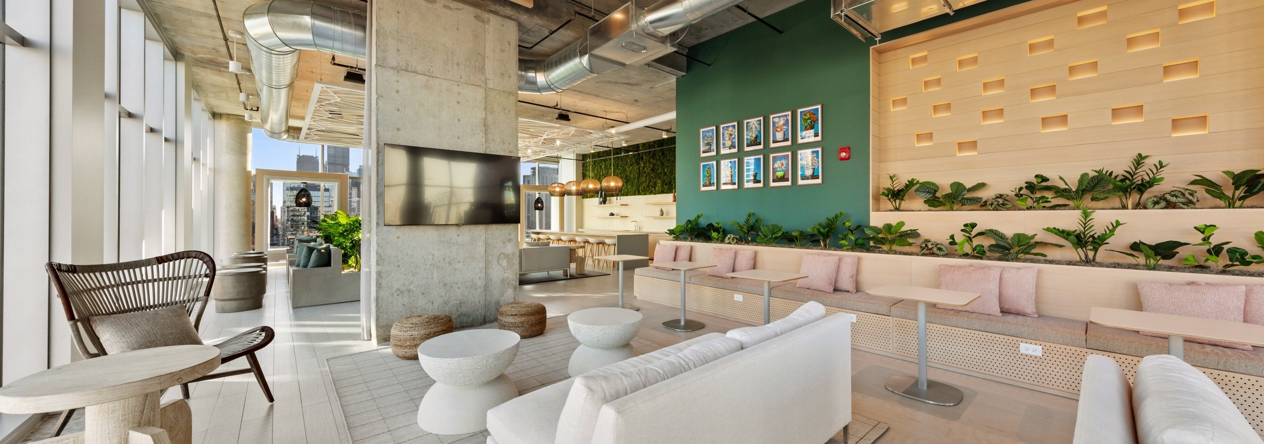 AMLI 808 resident lounge with neutral furnishings and a loft ceiling with vibrant green plants lining the wall in background