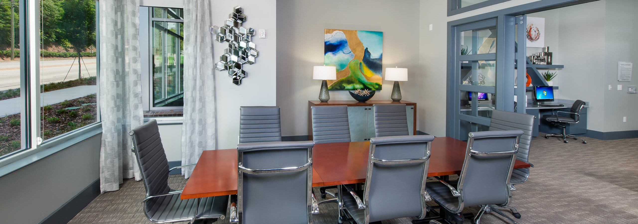 Conference room at AMLI Piedmont Heights apartment building with wood table and eight office chairs with artwork on walls