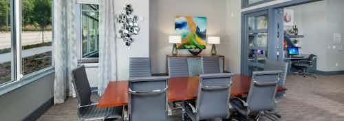 Conference room at AMLI Piedmont Heights apartment building with wood table and eight office chairs with artwork on walls