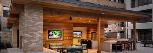 Exterior view of cabana at AMLI on Aldrich with colorful seating area and a flatscreen TV with barstools at counter