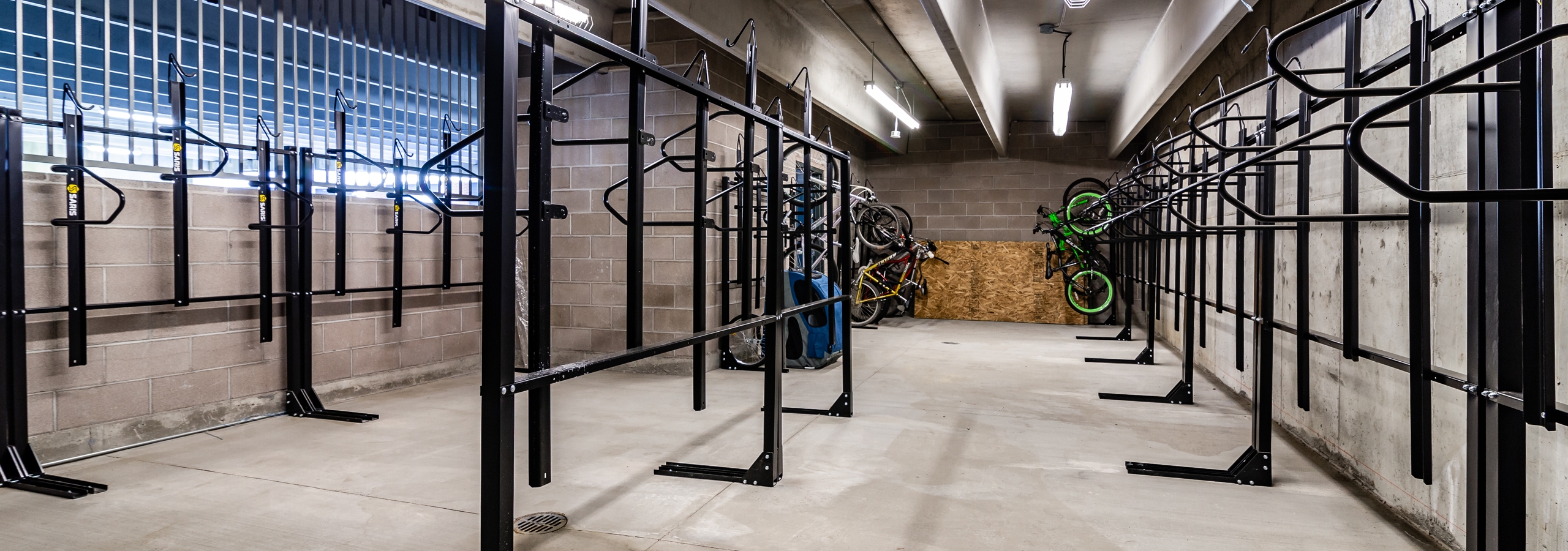 Interior of AMLI Littleton Village apartment building bike/ski/snowboard storage room with brick walls and ample bike racks