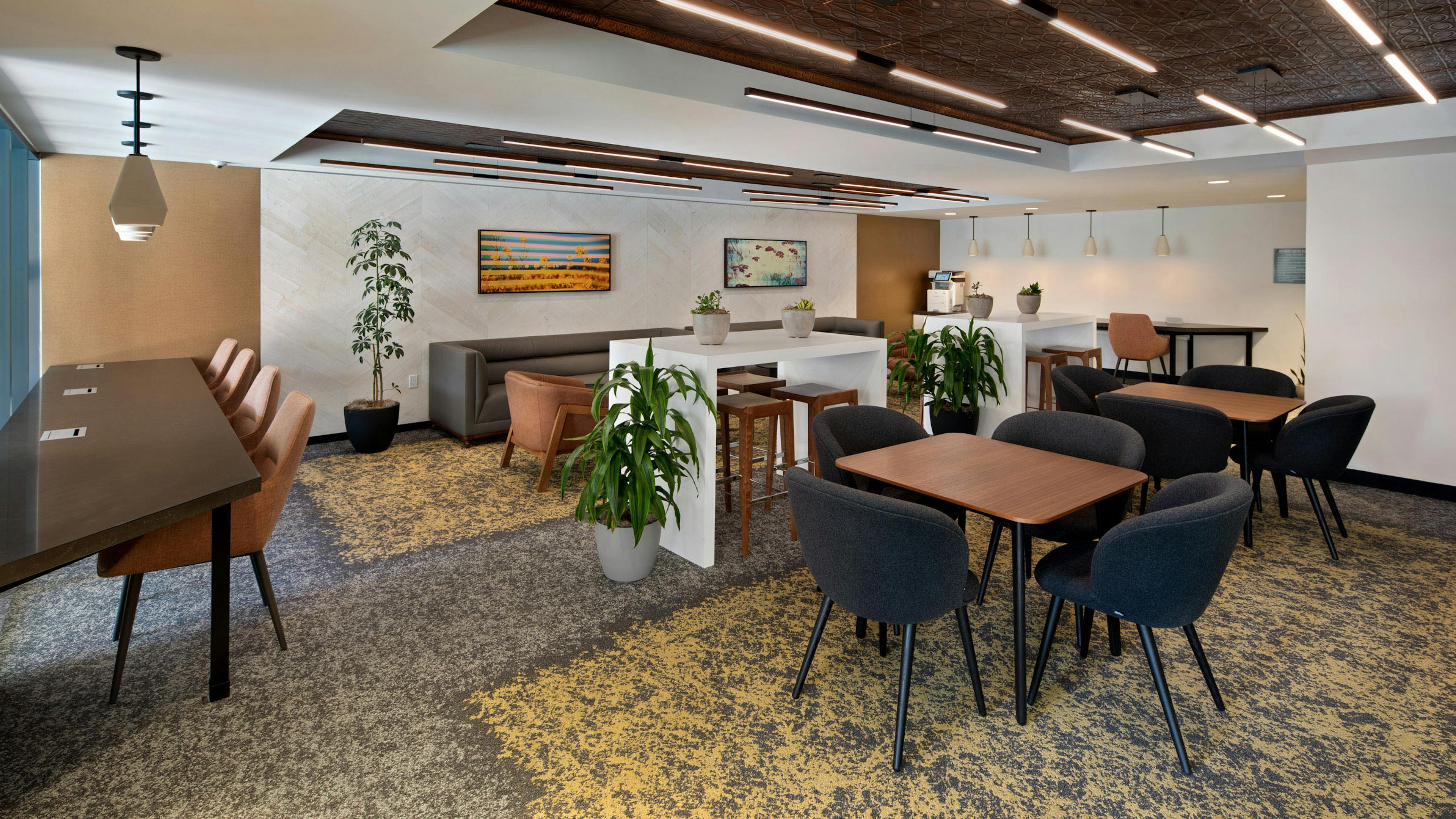 Interior view of business center at AMLI Old Pasadena apartments with a variety of workspaces and printer and potted plants