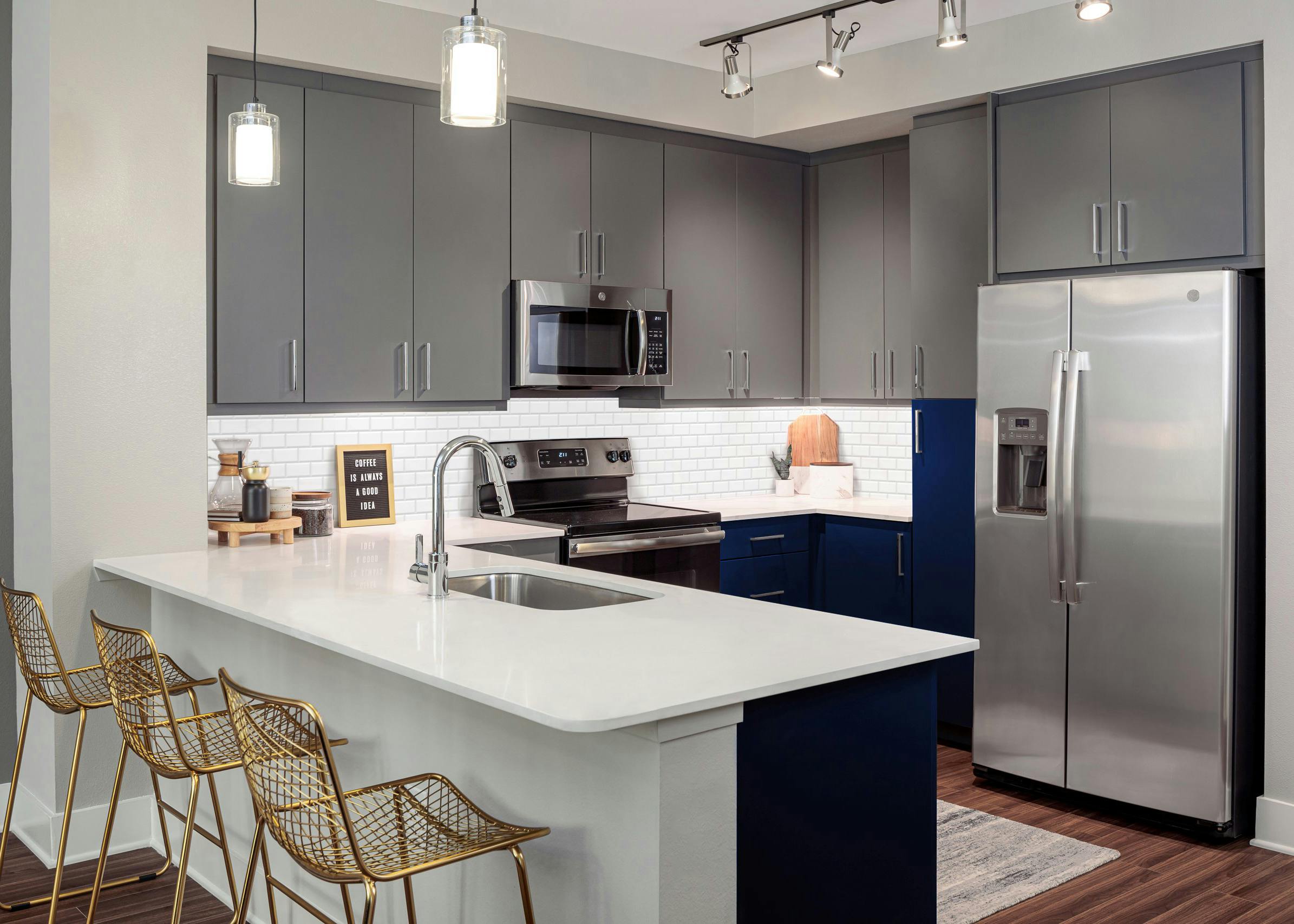 Kitchen at AMLI Branch Park apartments with gray cabinets and white countertops and stainless steel appliances