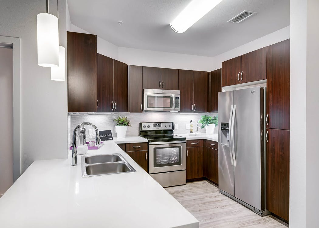A kitchen at AMLI Inverness apartments with a white granite counter top and stainless steel fixtures and overhead lighting