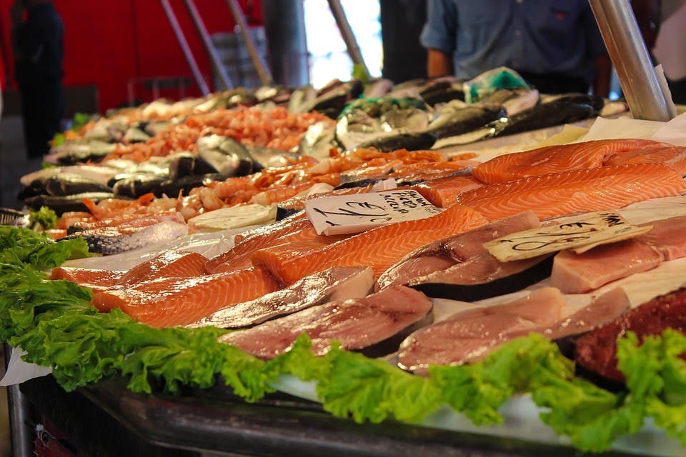 A market table covered with cuts of fish and green lettuce