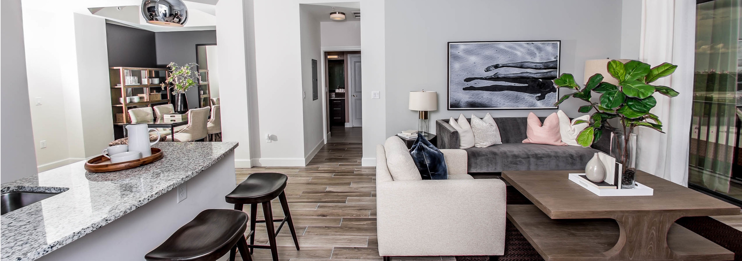 An apartment living room at AMLI Joya with cool neutral colors, a couch and coffee table and kitchen island with stools