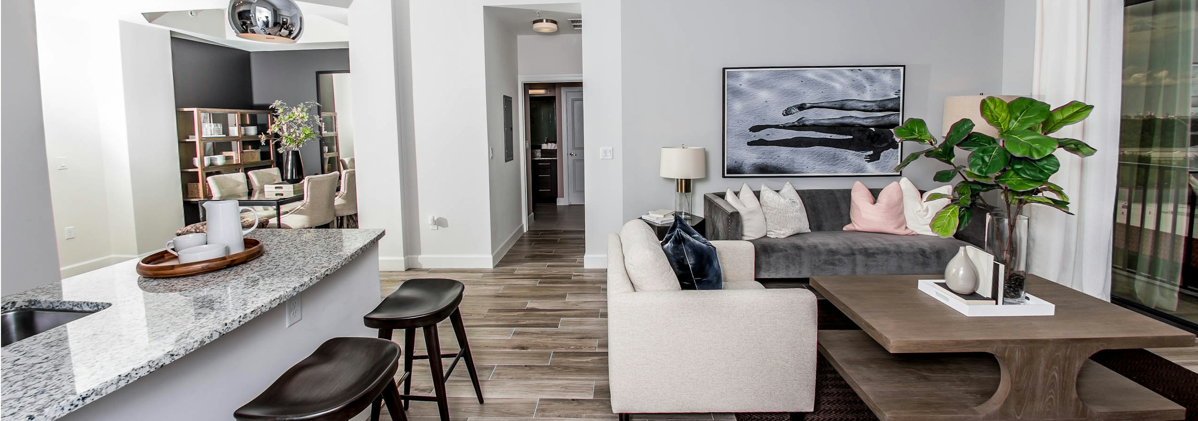  An apartment living room at AMLI Joya with cool neutral colors, a couch and coffee table and kitchen island with stools