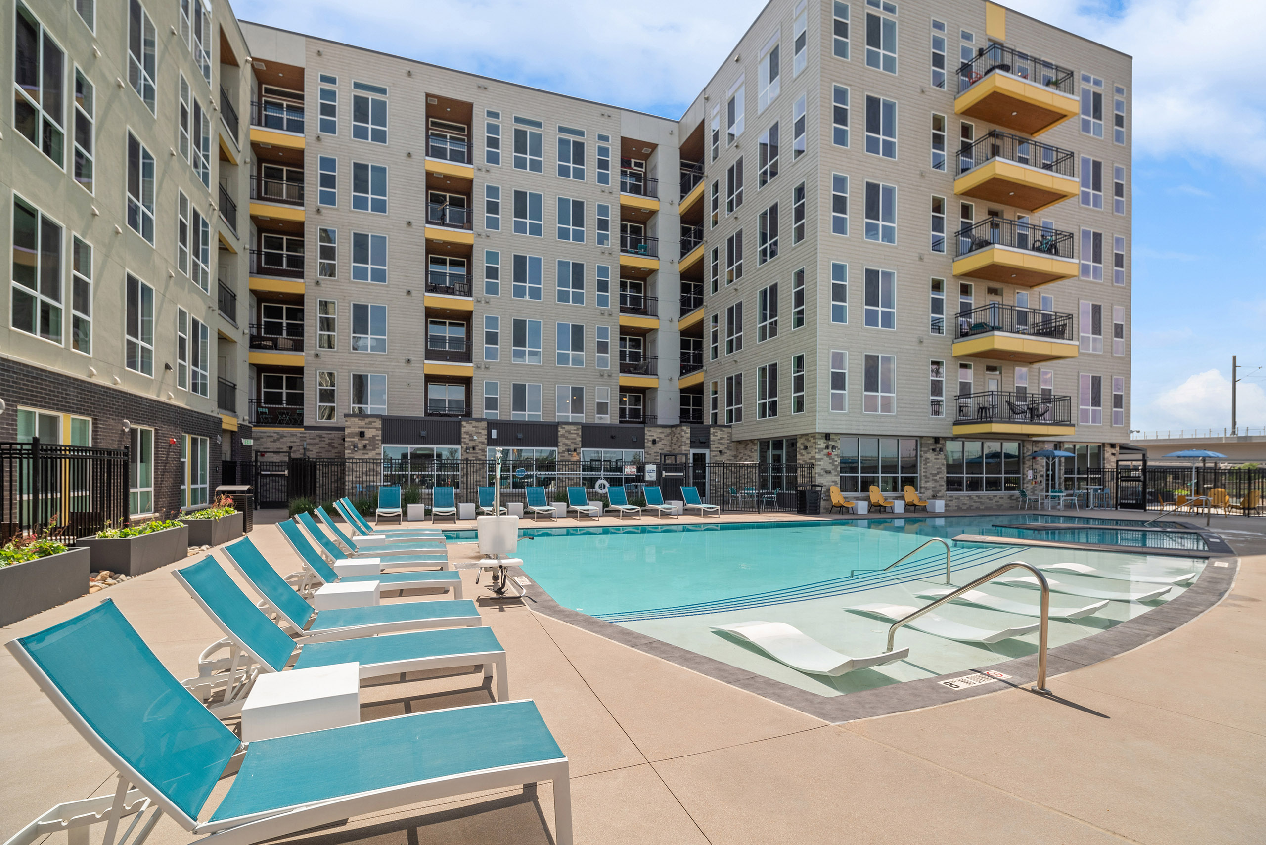 AMLI RiNo pool with lounge seating inside and outside of water and beige and brown building with yellow balconies