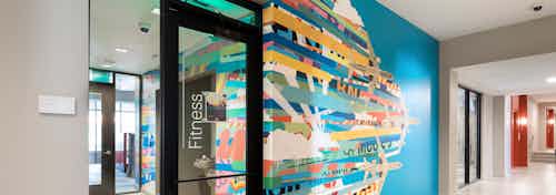Interior view of AMLI on Aldrich neutral hallway area with a colorful patterned blue accent wall and a large glass door