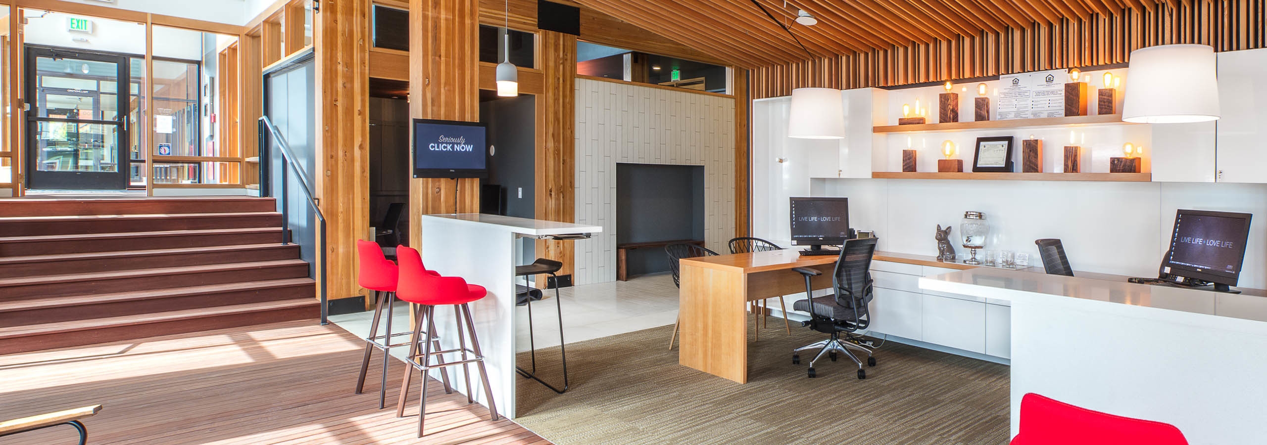 The leasing office at AMLI Wallingford with high ceilings seating bright walls and lots of natural wood on stairs floor and ceiling