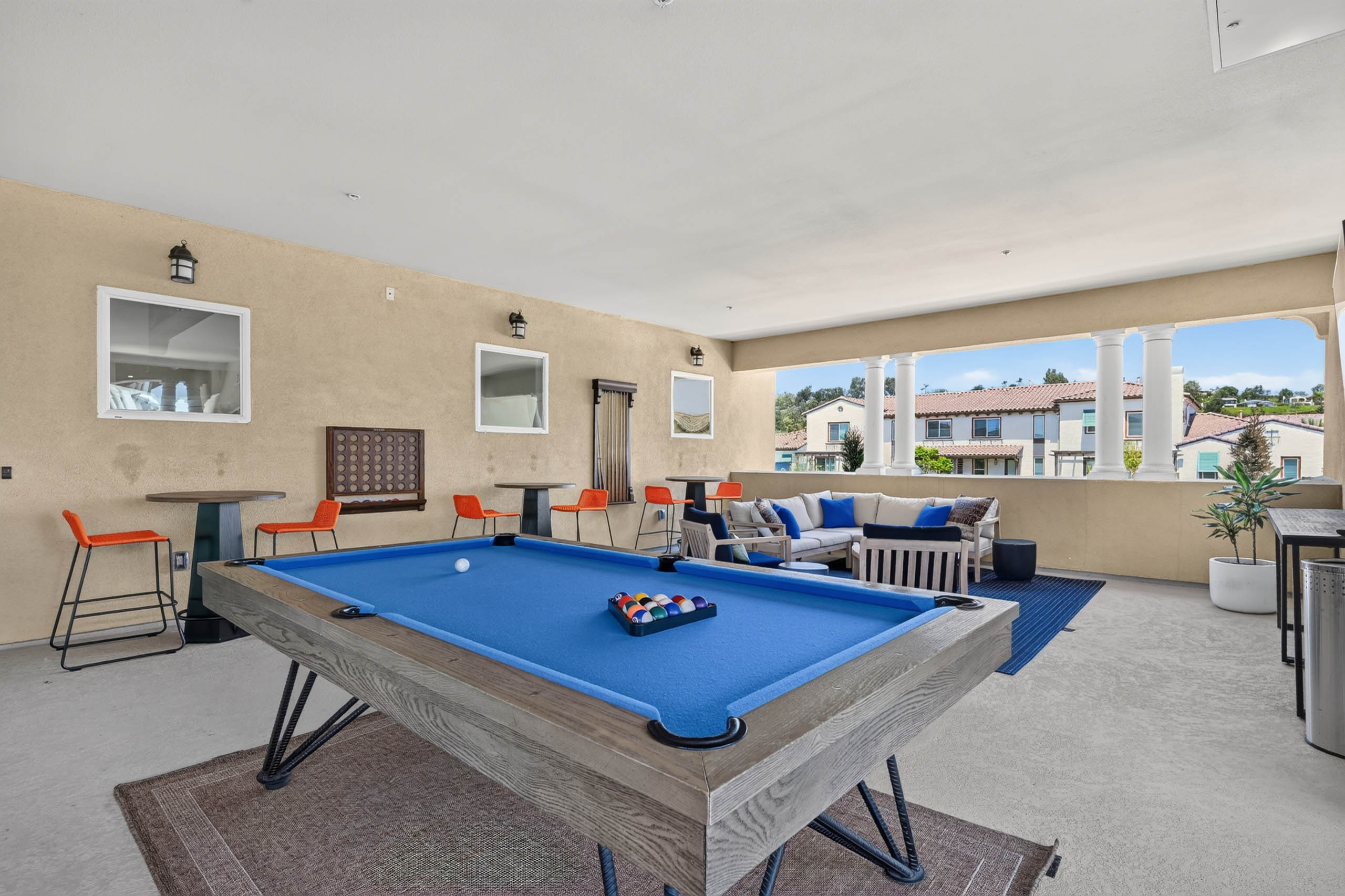 Second floor game loung at AMLI Camarillo apartments with blue billiards table, lounge seating, high top tables and courtyard views.