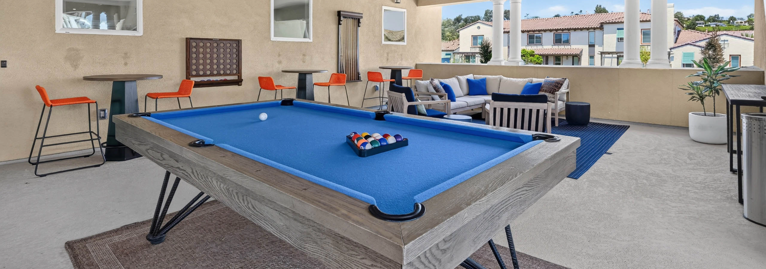 Second floor game loung at AMLI Camarillo apartments with blue billiards table, lounge seating, high top tables and courtyard views.