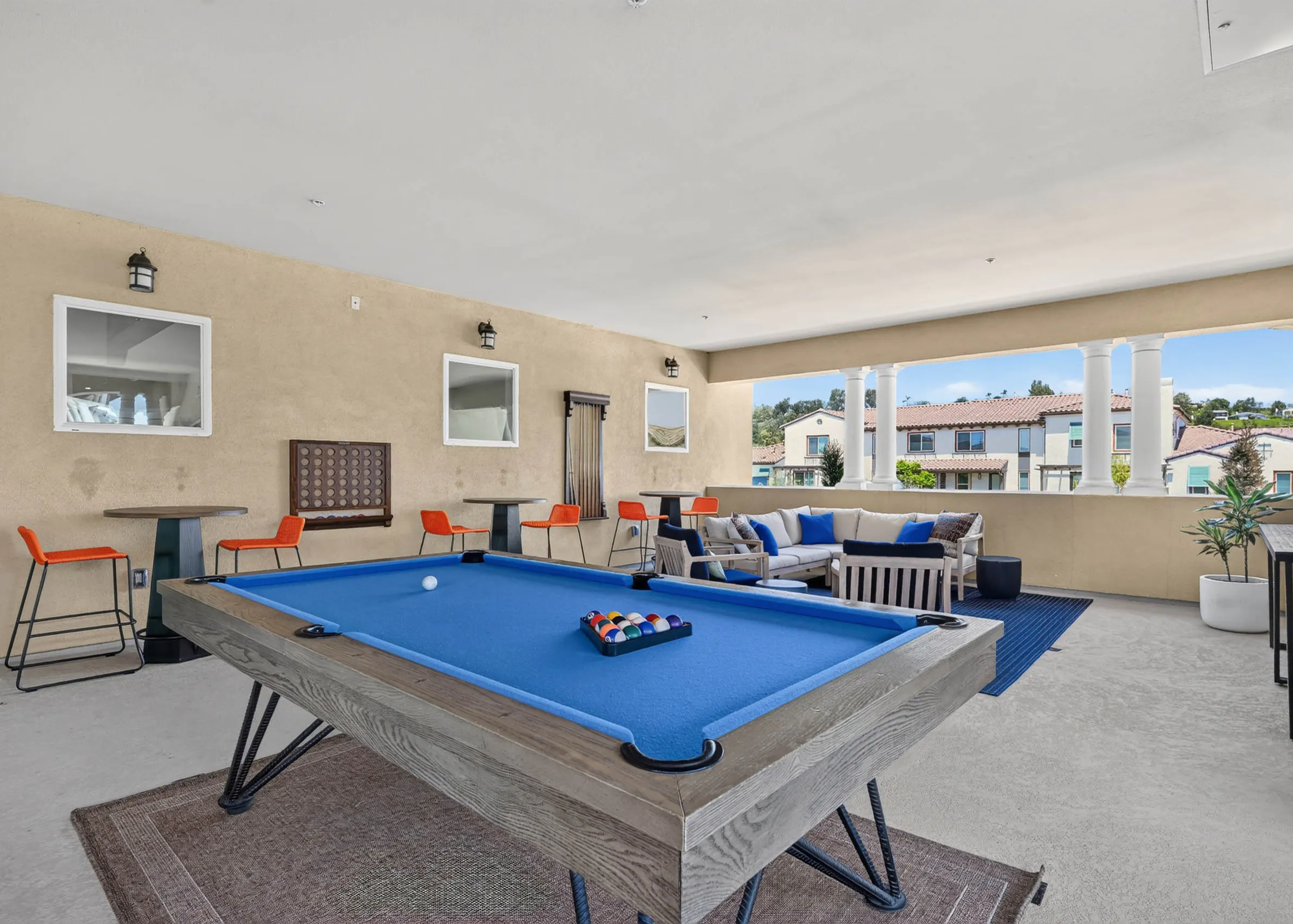 Second floor game loung at AMLI Camarillo apartments with blue billiards table, lounge seating, high top tables and courtyard views.