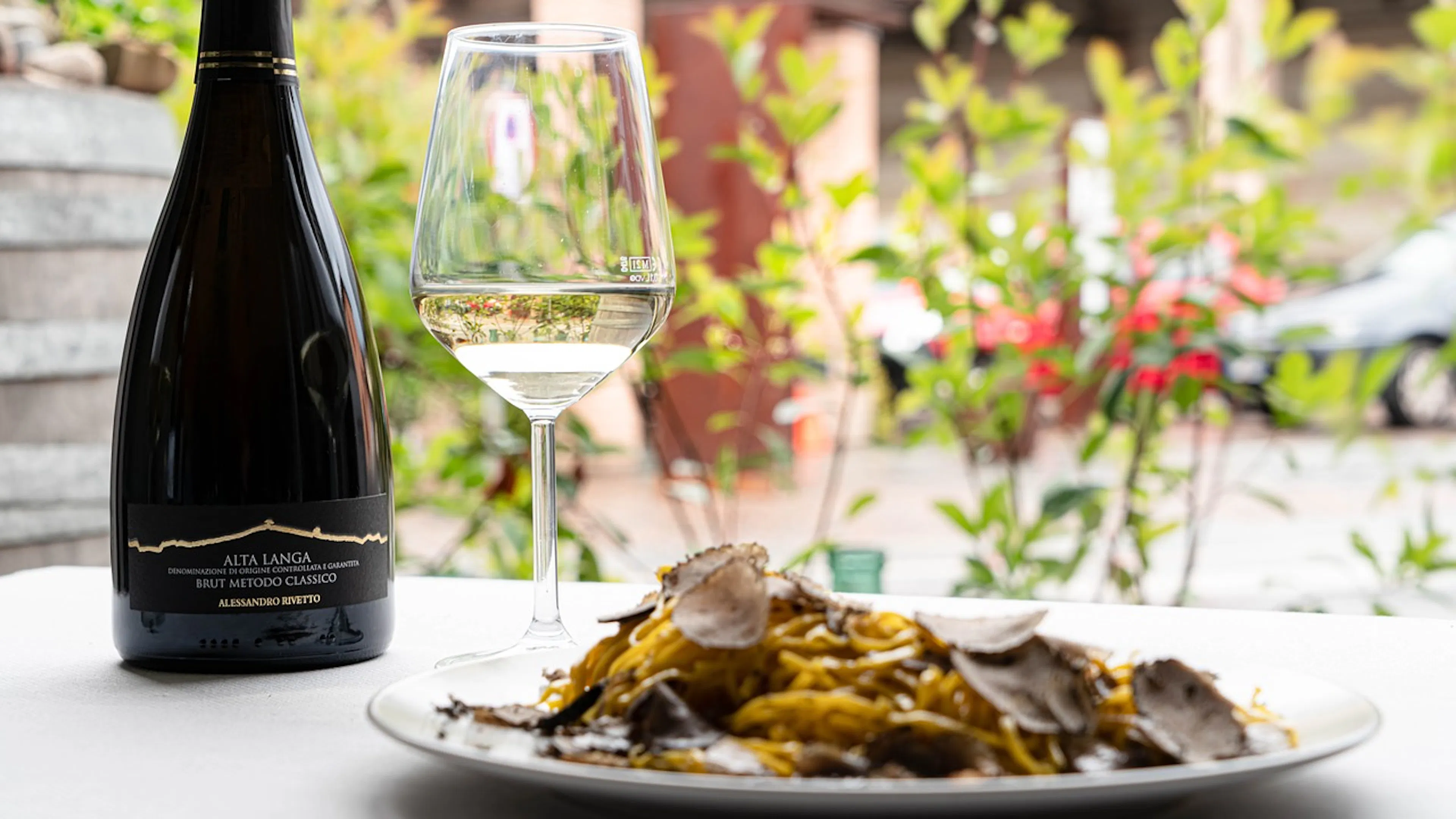 A plate of seafood pasta in front of a glass and bottle of white sparkling wine