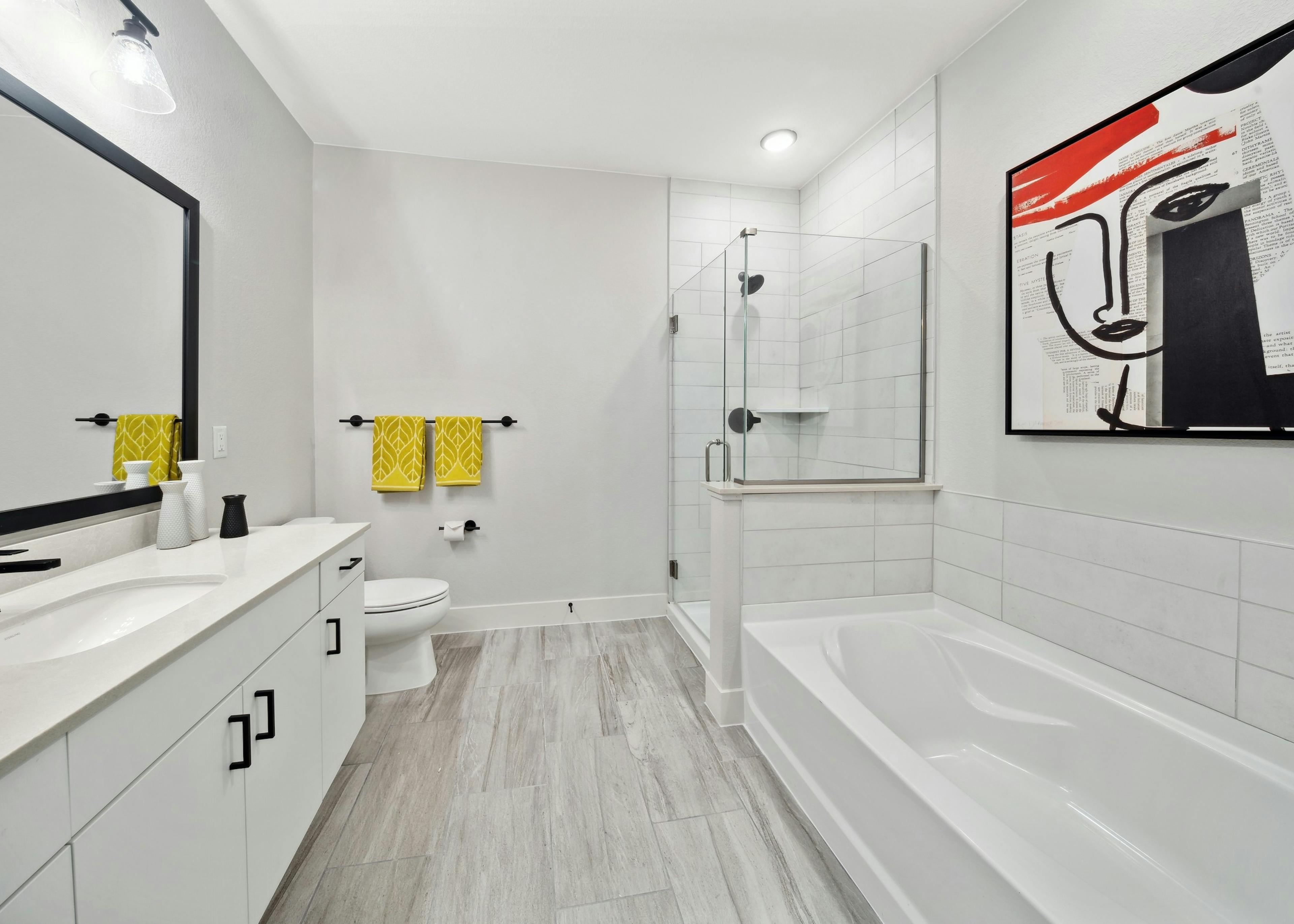 Bathroom at AMLI RiNo with large white tile shower and tub surrounds and white vanity with black hardware and gray wood floors